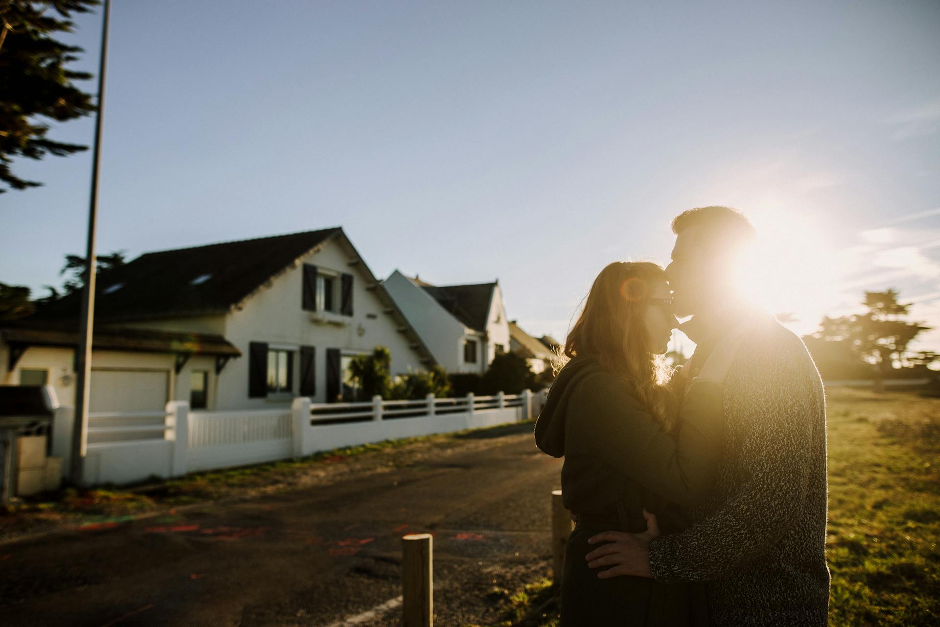 Un homme embrassant une femme sur le front devant une maison | Source : Pexels