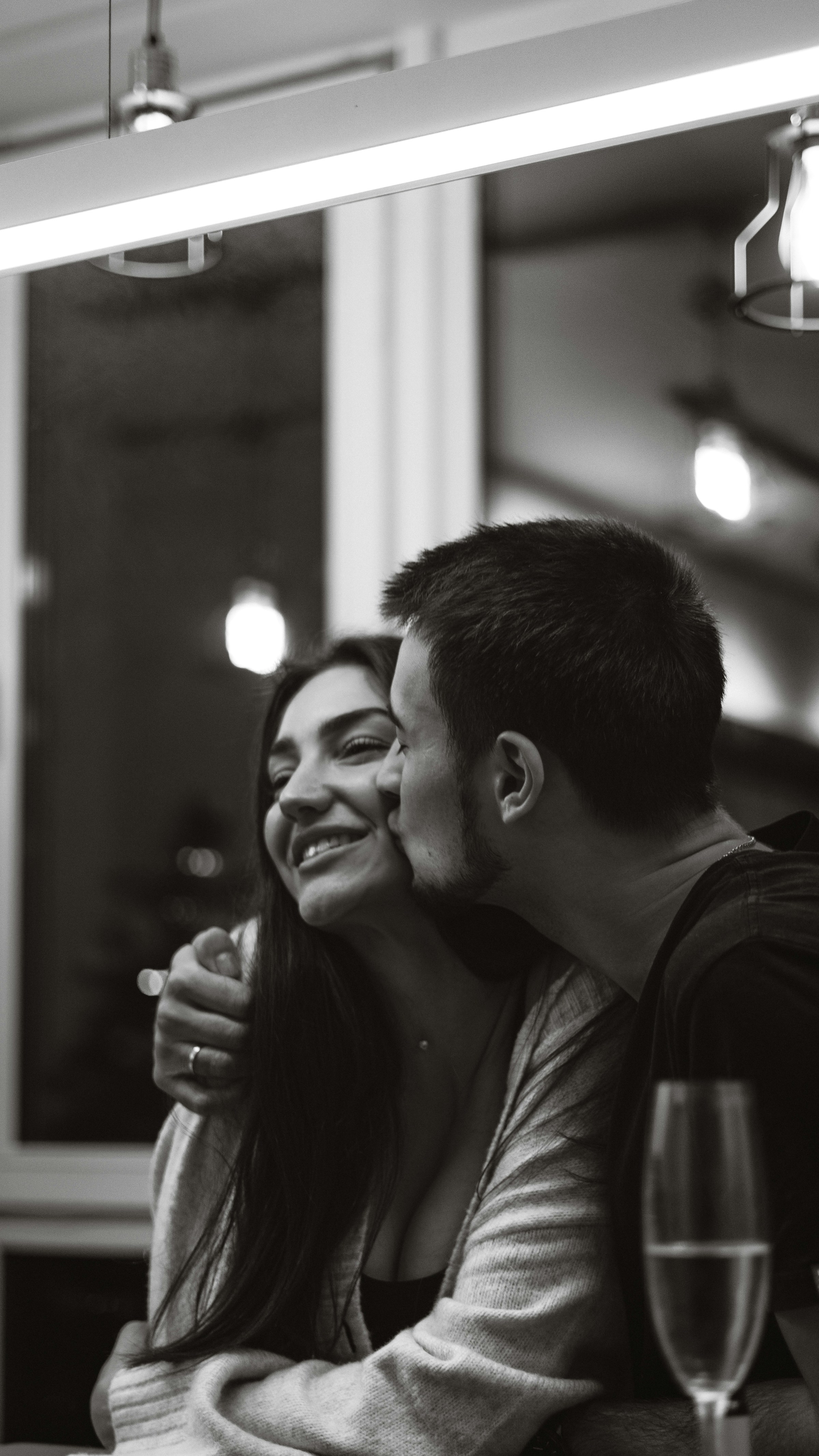 Photo en niveaux de gris d'un homme embrassant une femme sur la joue | Source : Unsplash
