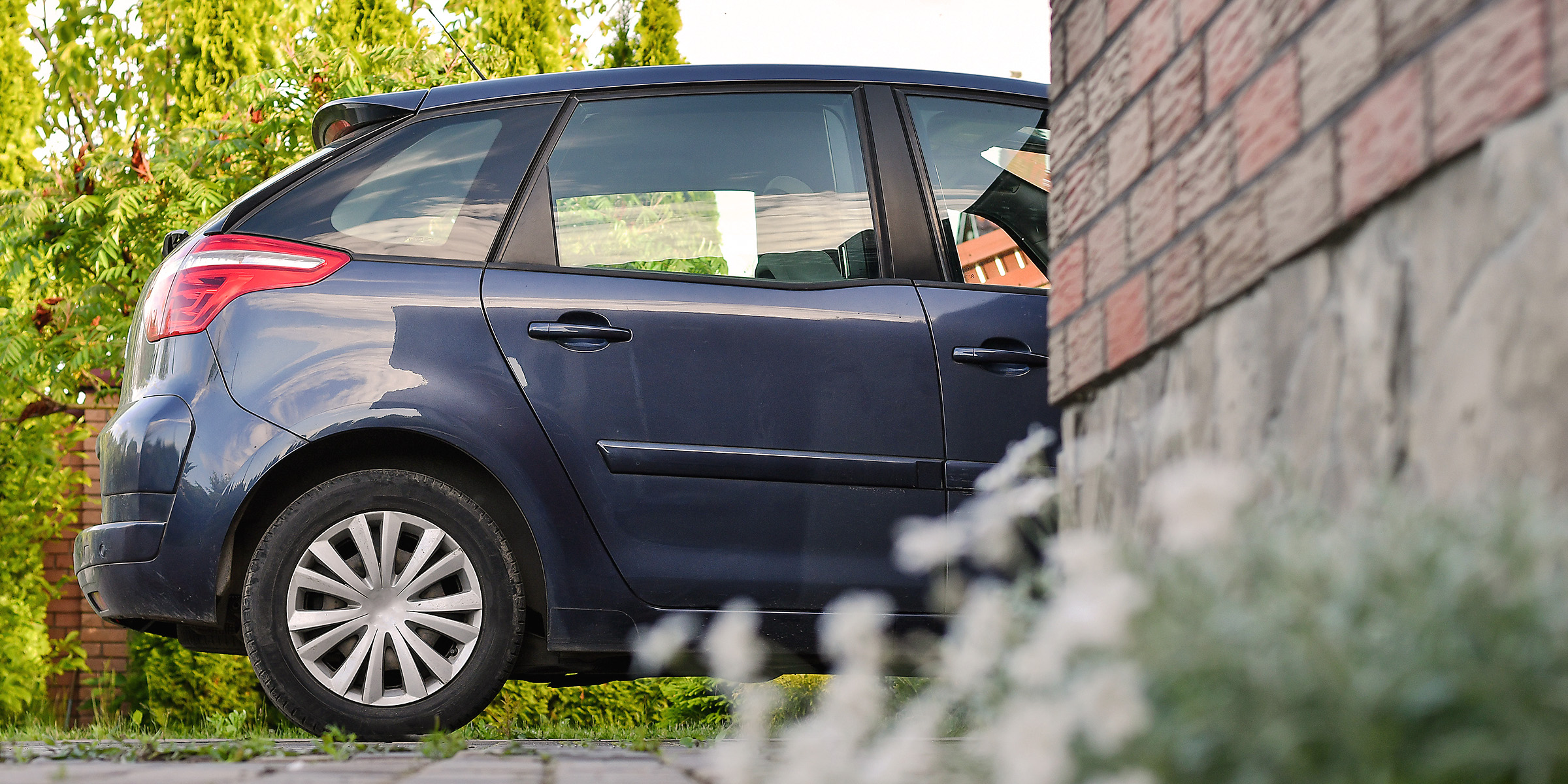 Une voiture bleu foncé garée à côté d'un mur de briques dans un quartier tranquille | Source : Shutterstock