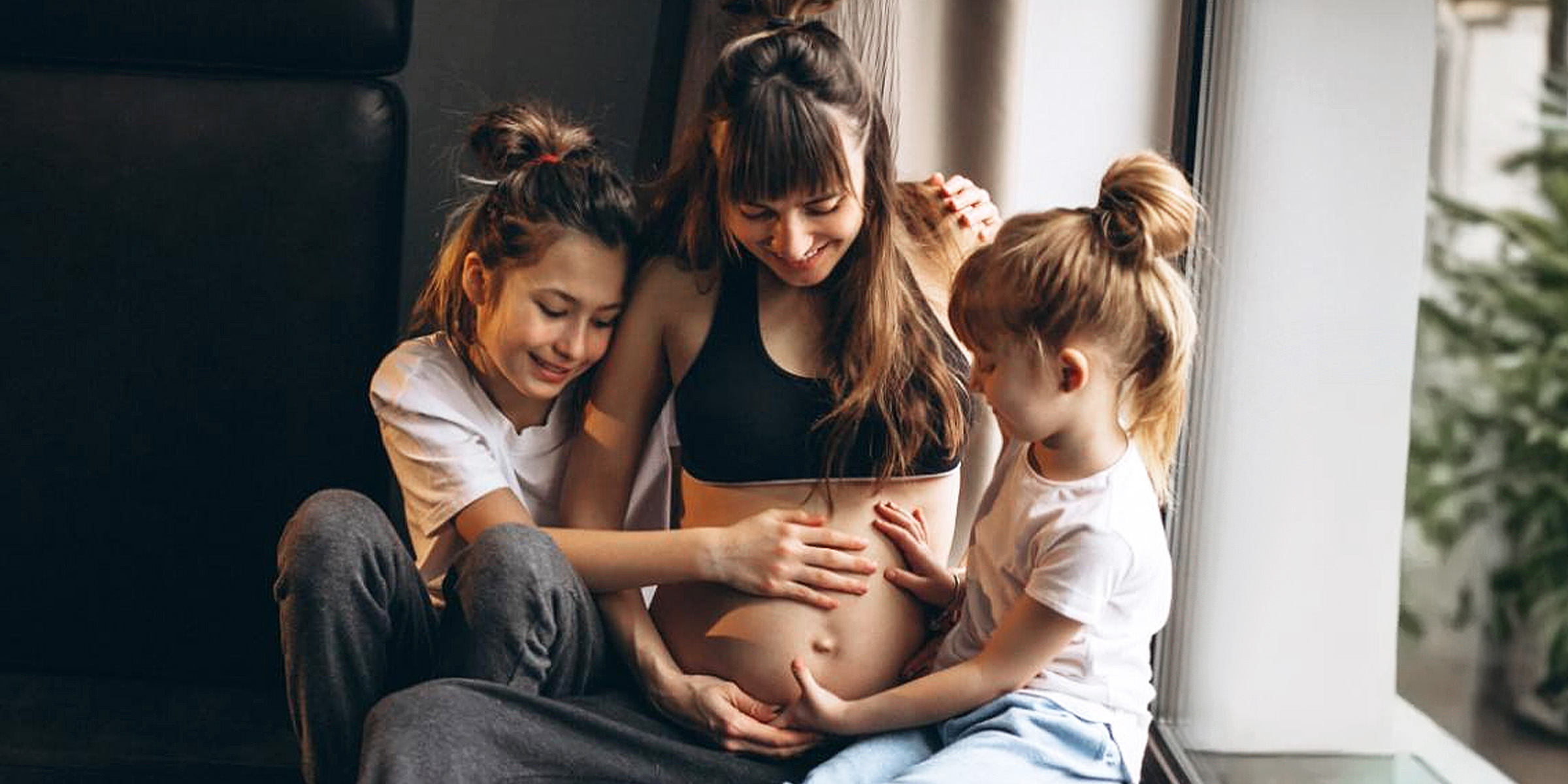 Une femme enceinte avec des enfants assis près de la fenêtre | Source : Freepik