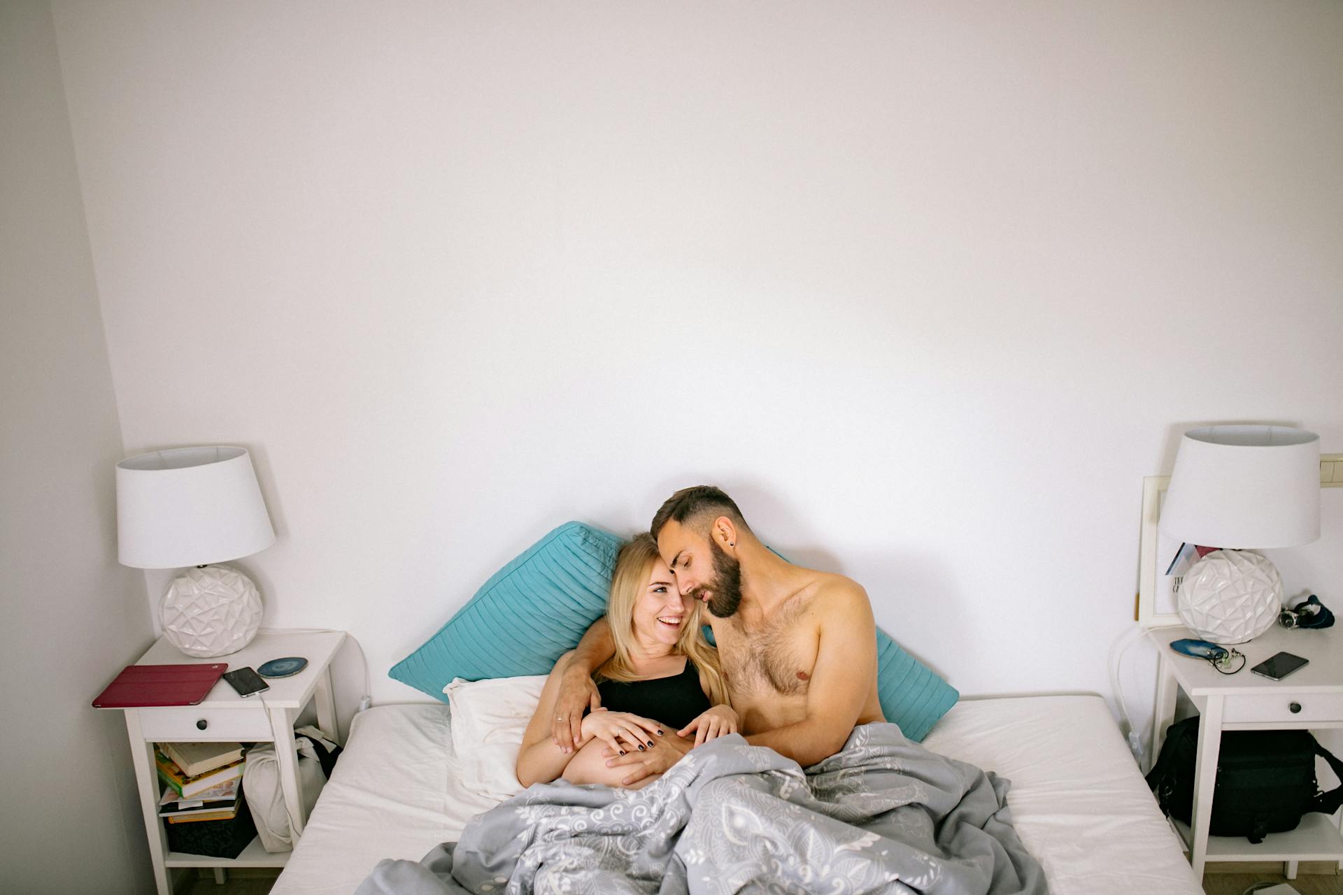 Un mari qui touche le baby bump de sa femme enceinte tout en se câlinant au lit | Source : Pexels