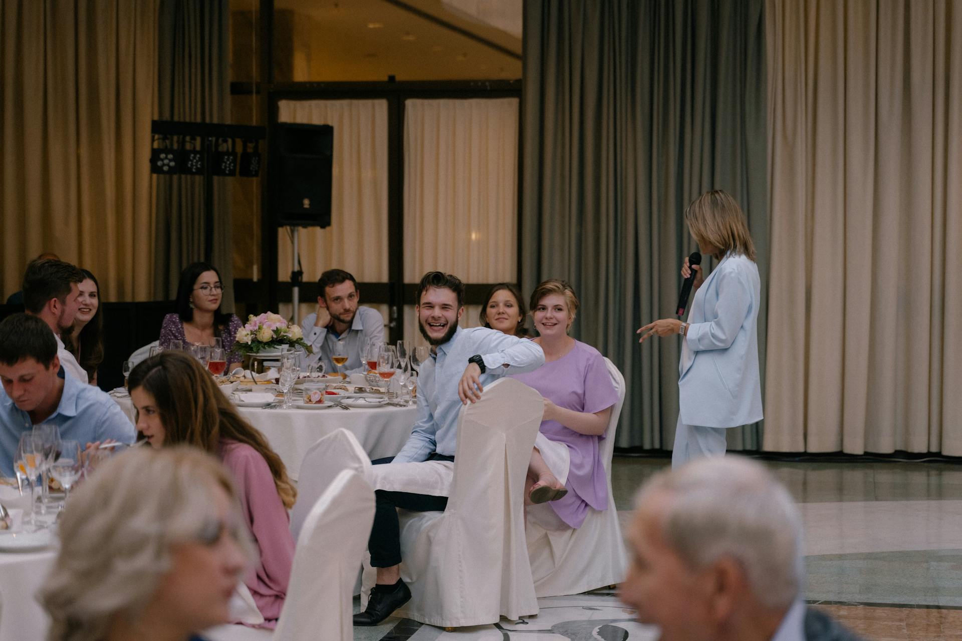 Des invités vus en train de rire pendant qu'une femme prononce un discours au micro | Source : Pexels