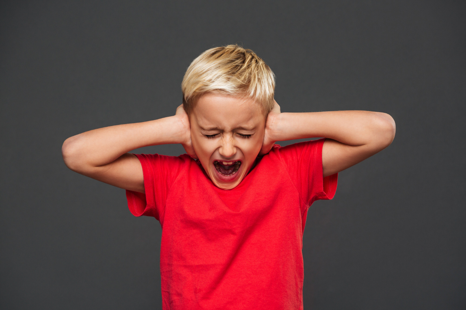 Un jeune garçon qui crie en se bouchant les oreilles | Source : Freepik