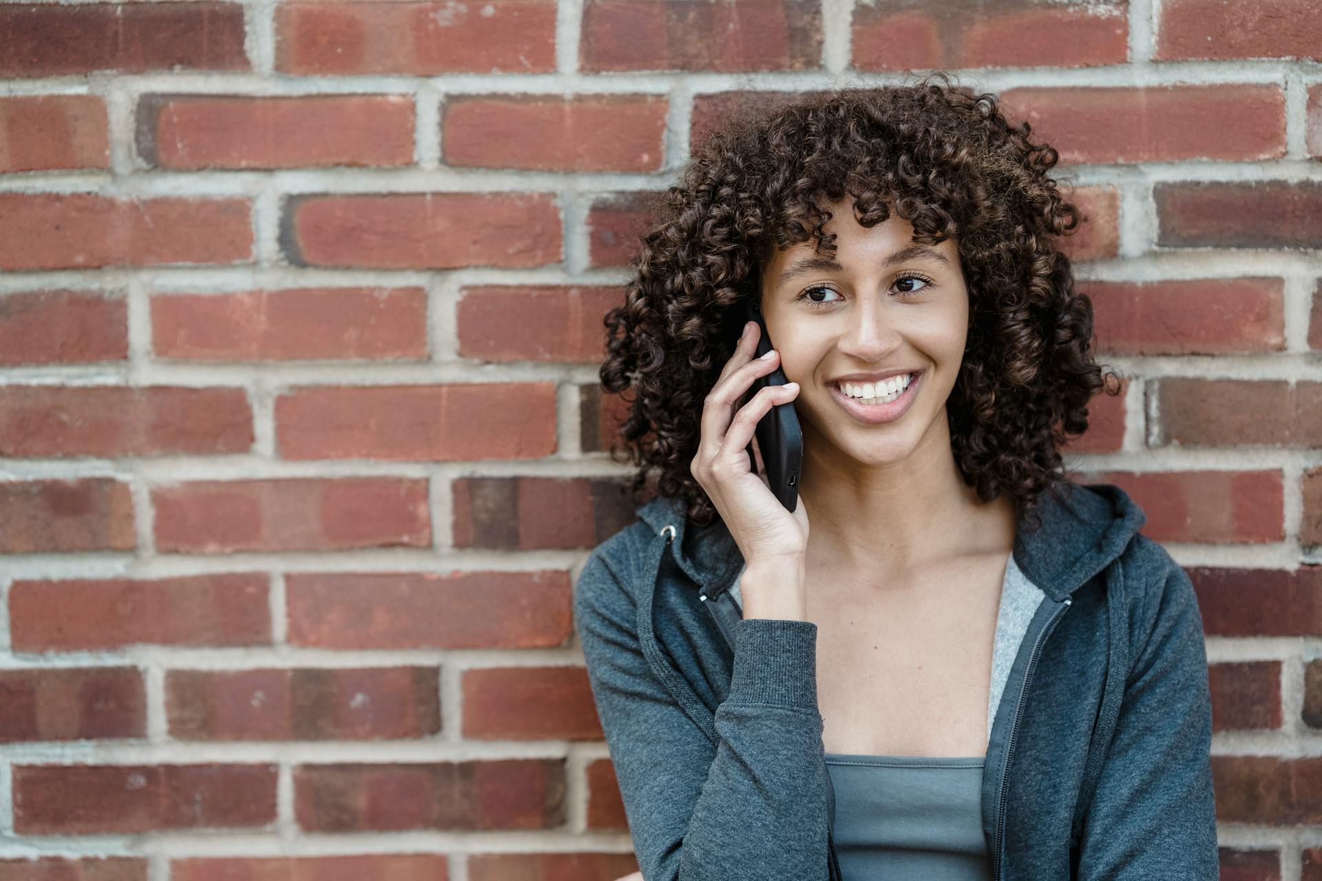Une femme qui répond au téléphone en souriant | Source : Pexels
