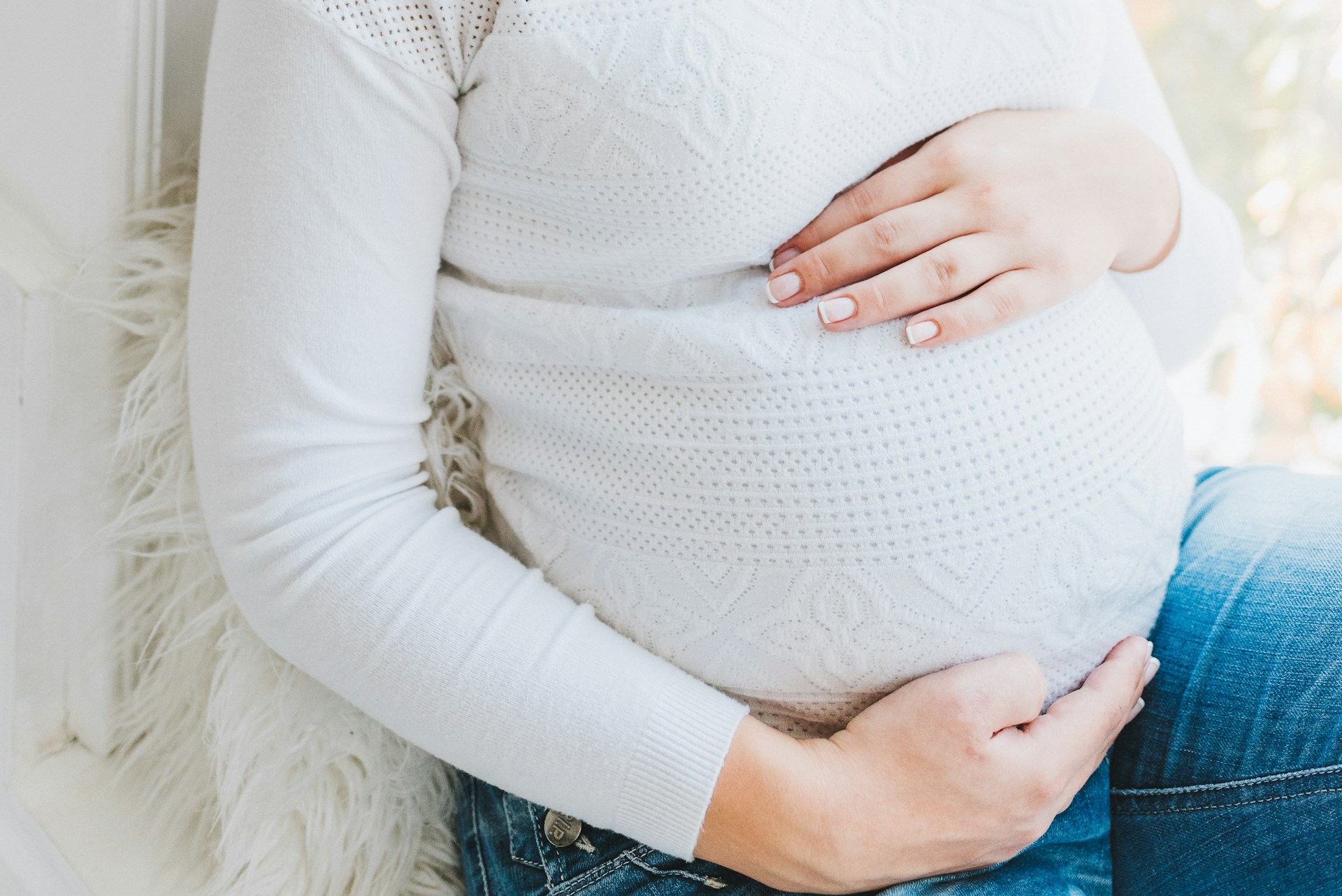 Une femme enceinte assise avec ses mains sur son ventre | Source : Unsplash