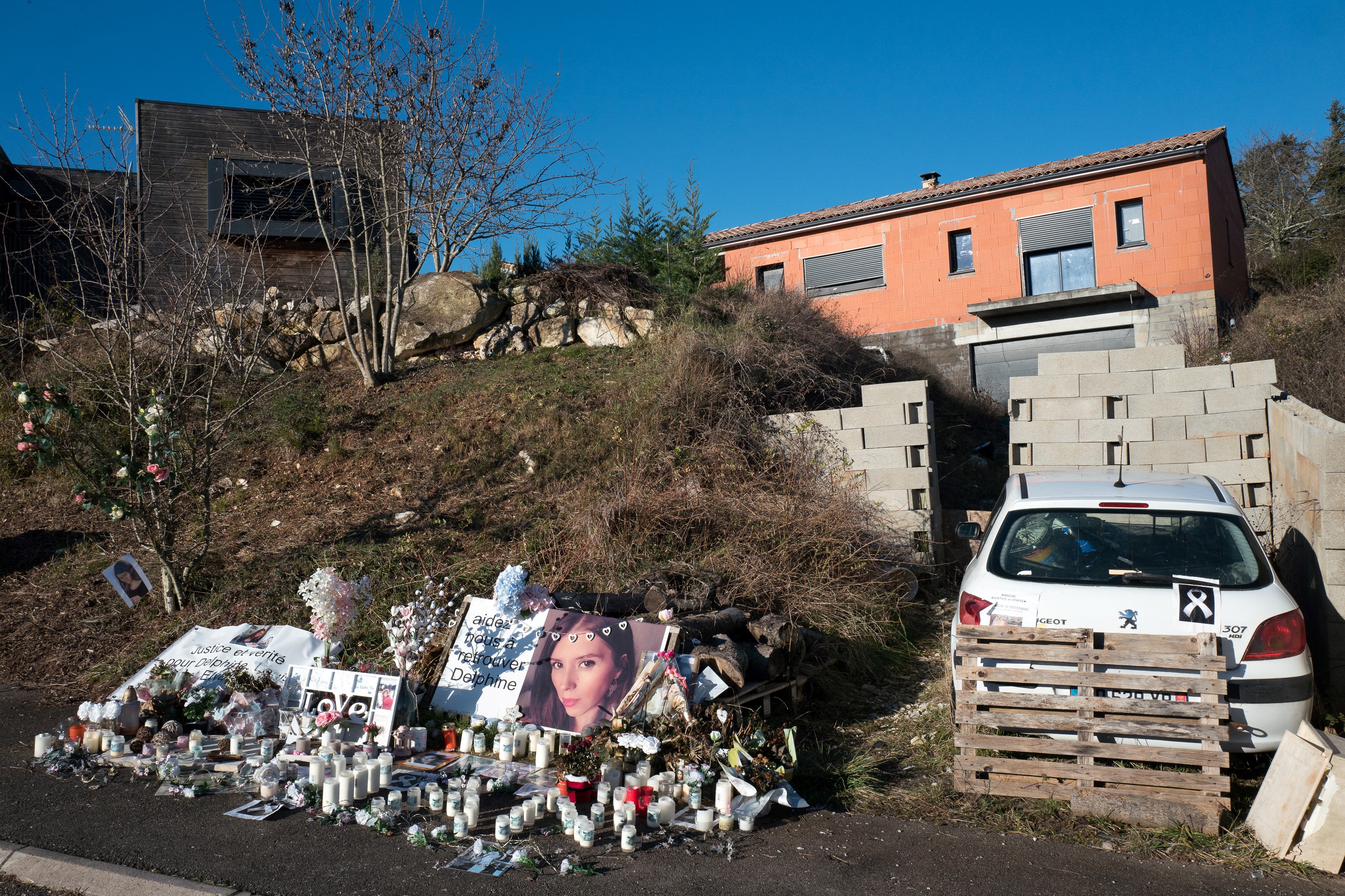 Une photo prise le 24 janvier 2022 montre des bougies et des fleurs déposées devant la maison de Delphine (portrait) et Cédric Jubillar à Cagnac-les-Mines, alors que des recherches sont menées dans la région pour retrouver le corps de l'infirmière de 33 ans disparue en France en décembre 2020 I Source : Getty Images