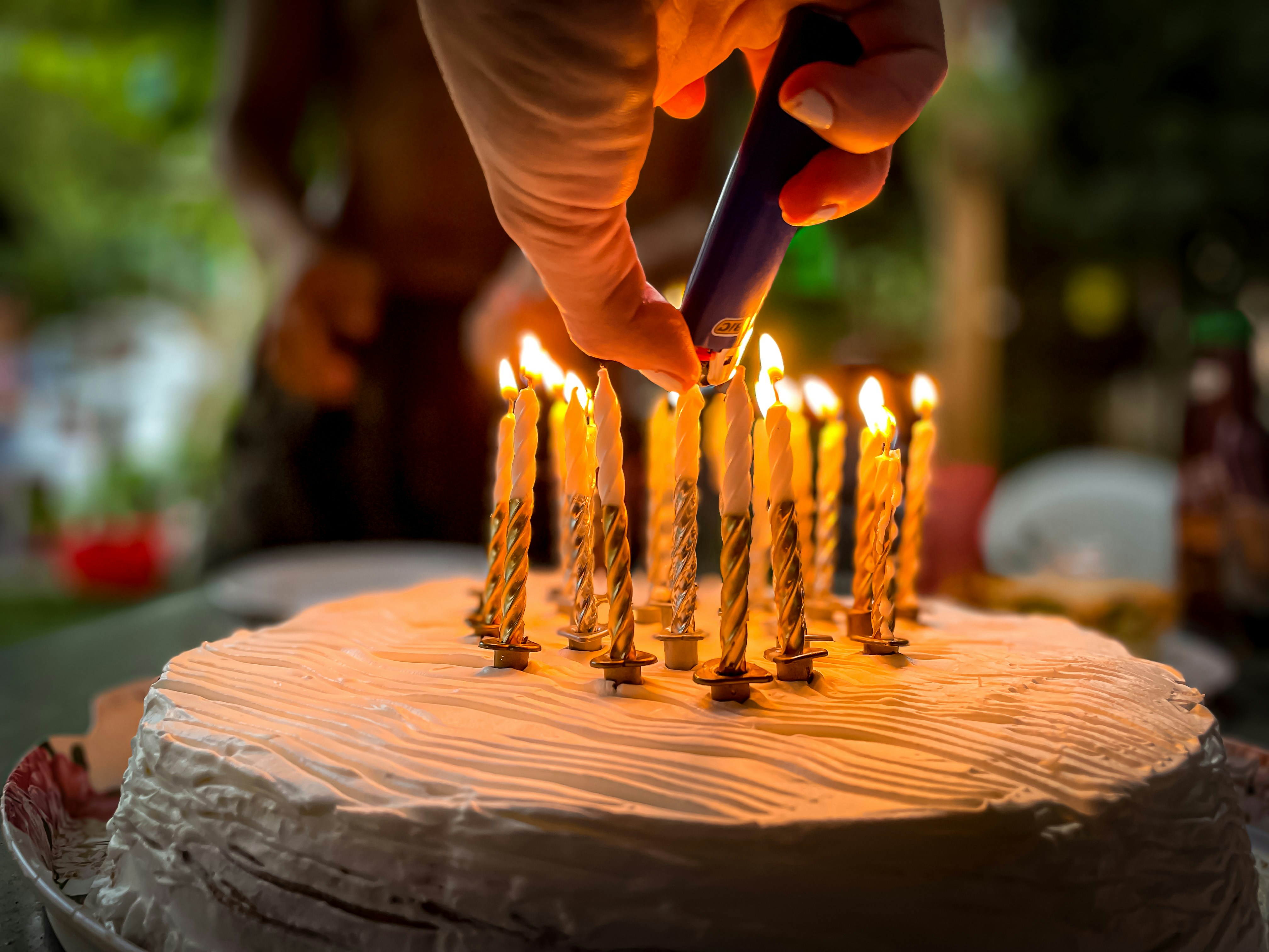 La main d'une femme allumant des bougies sur un gâteau | Source : Unsplash