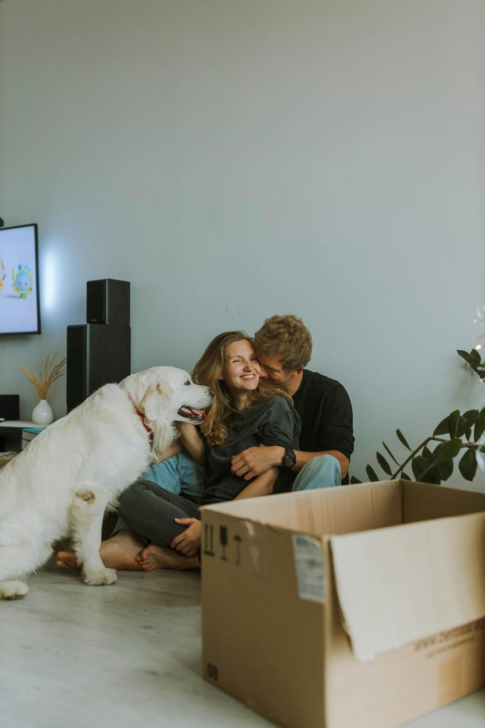 Un couple heureux se câlinant avec leur chien à leurs côtés | Source : Pexels