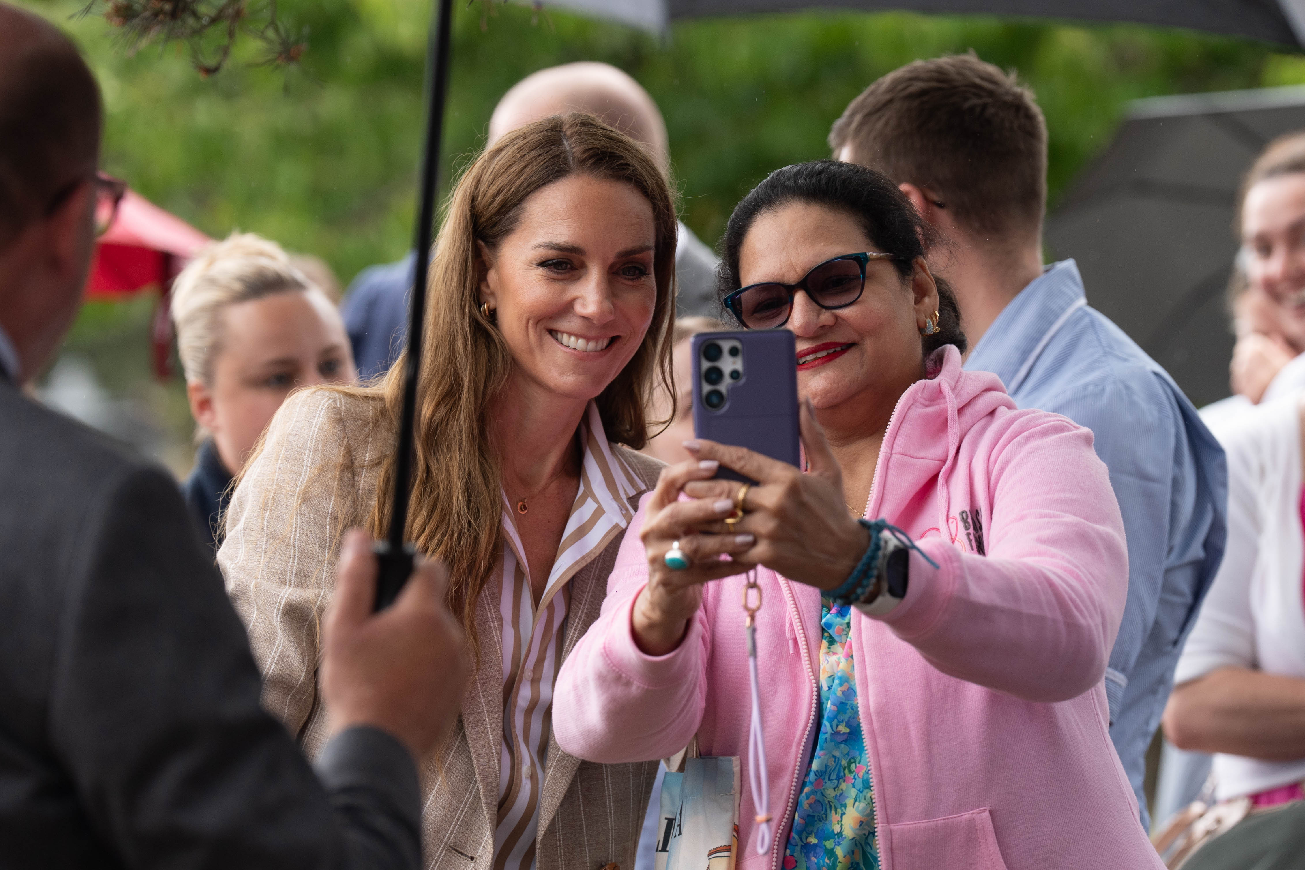La princesse Catherine partage un moment joyeux en prenant un selfie avec une admiratrice. Malgré la pluie, son énergie gracieuse a réchauffé le cœur de ceux qui s'étaient rassemblés dehors pour la rencontrer.
