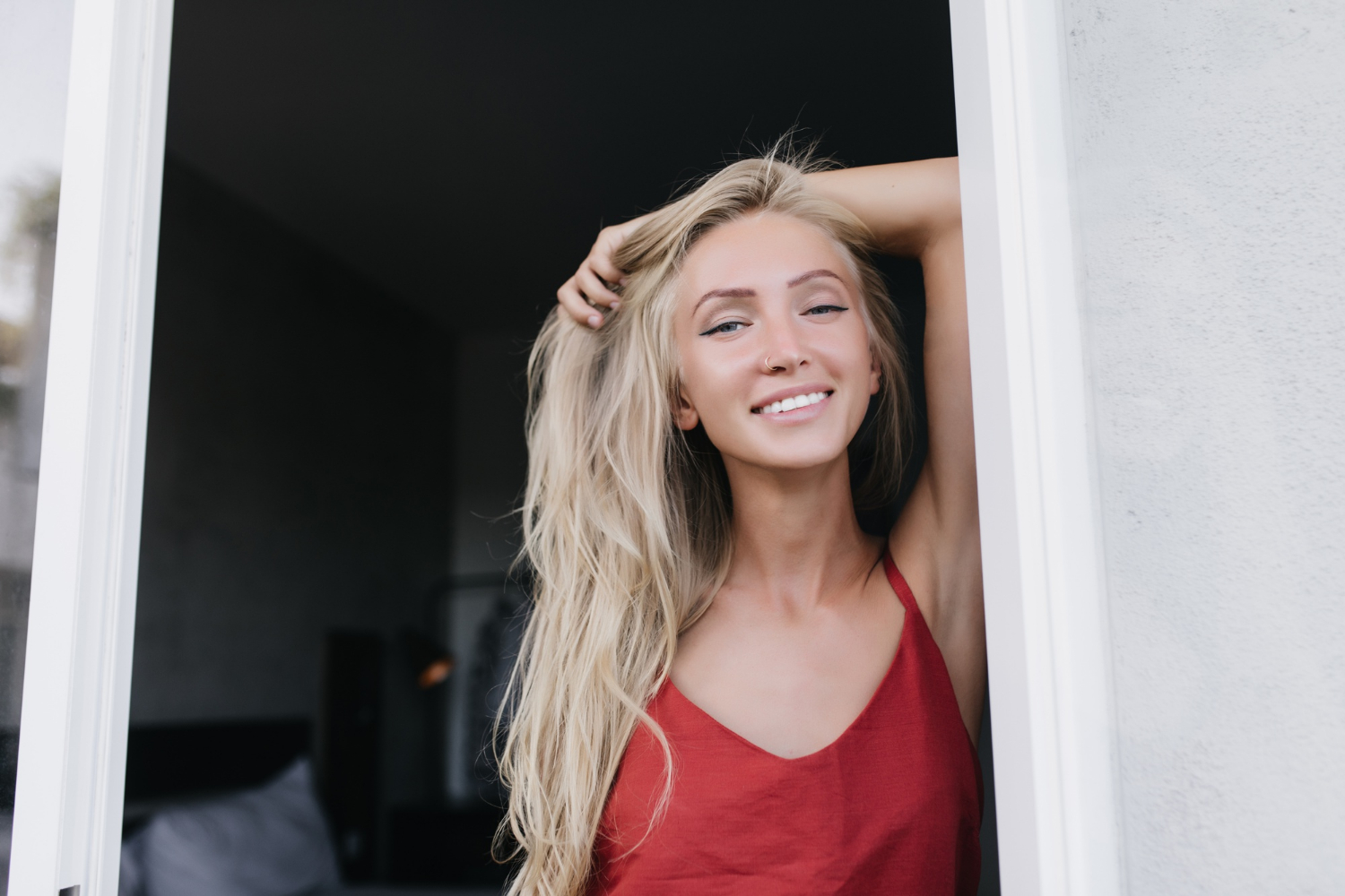 Une femme souriante se tenant à l'entrée d'une maison | Source : Freepik