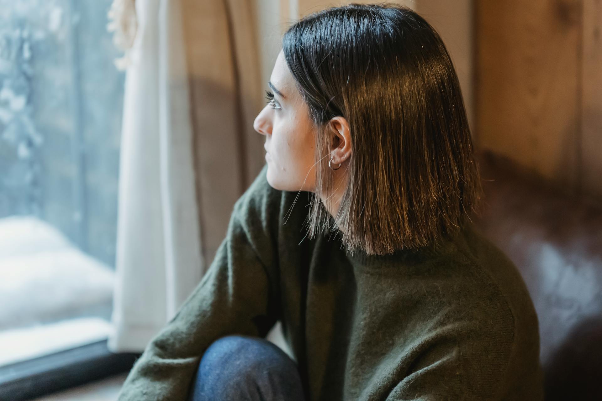 Une femme pensive assise près de la fenêtre | Source : Pexels