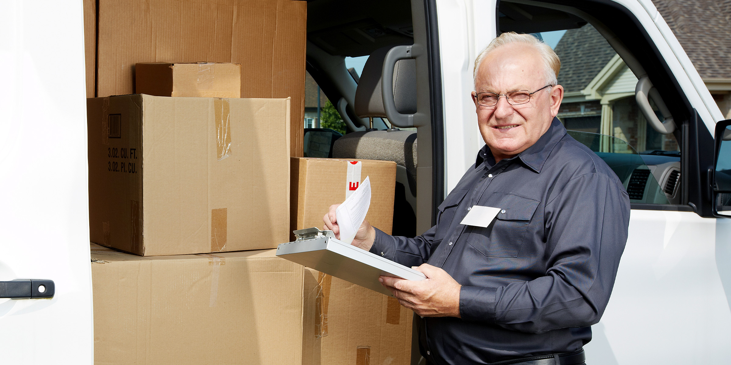 Un facteur debout à côté d'un véhicule | Source : Shutterstock
