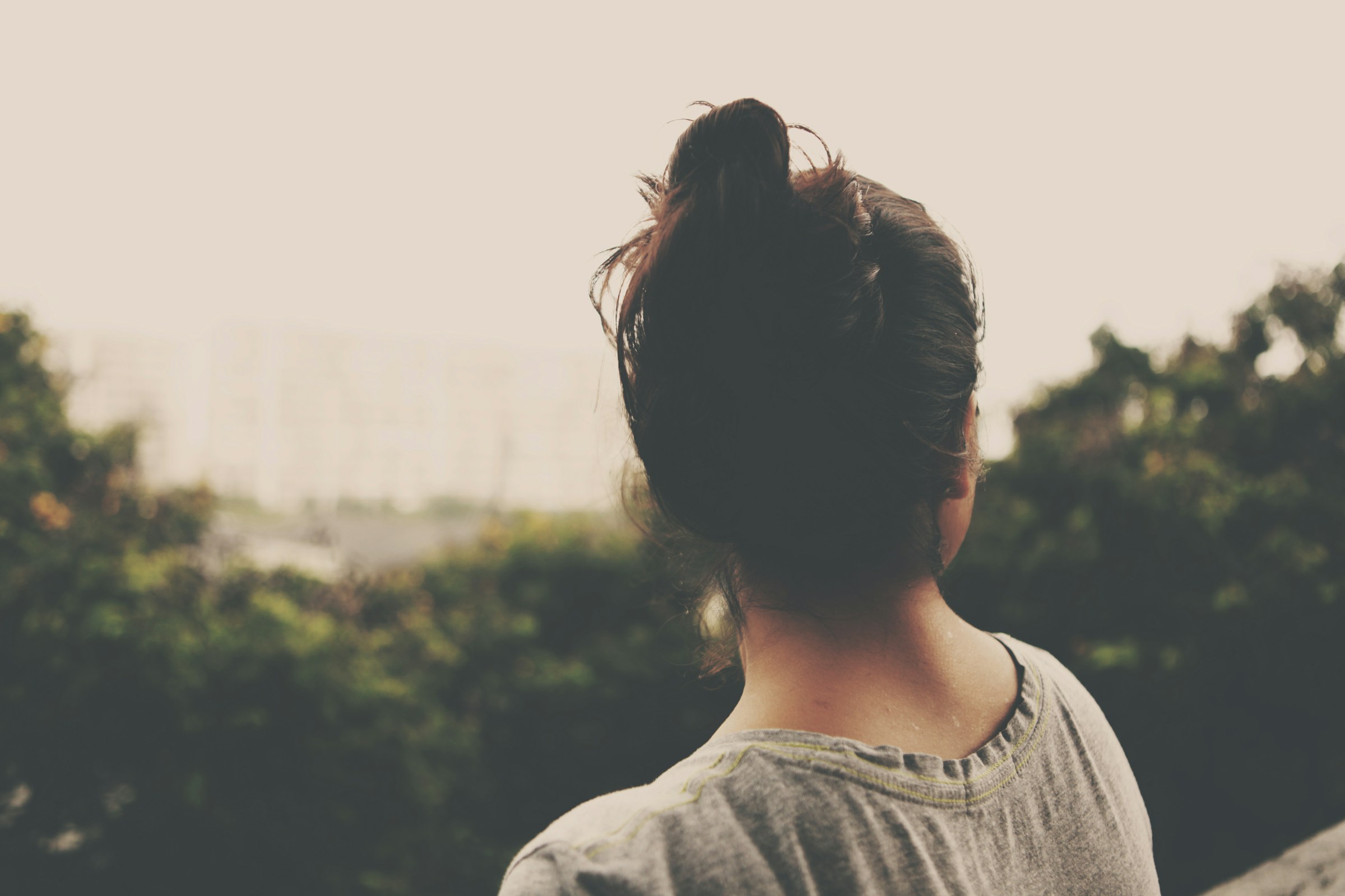 Une femme assise dehors en train de regarder les arbres | Source : Unsplash
