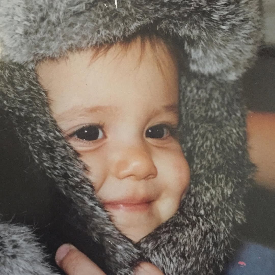 Ariana Grande enfant, emmitouflée dans une capuche douce et douillette. Son sourire aux fossettes et ses grands yeux pleins de chaleur et d'étincelles précoces | Source : Instagram/arianagrande