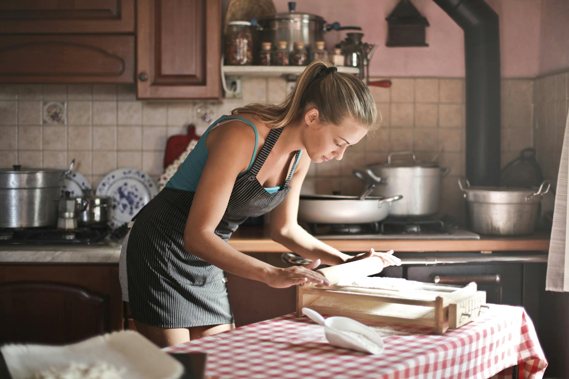 Une jeune femme roule de la pâte dans une cuisine | Source : Pexels