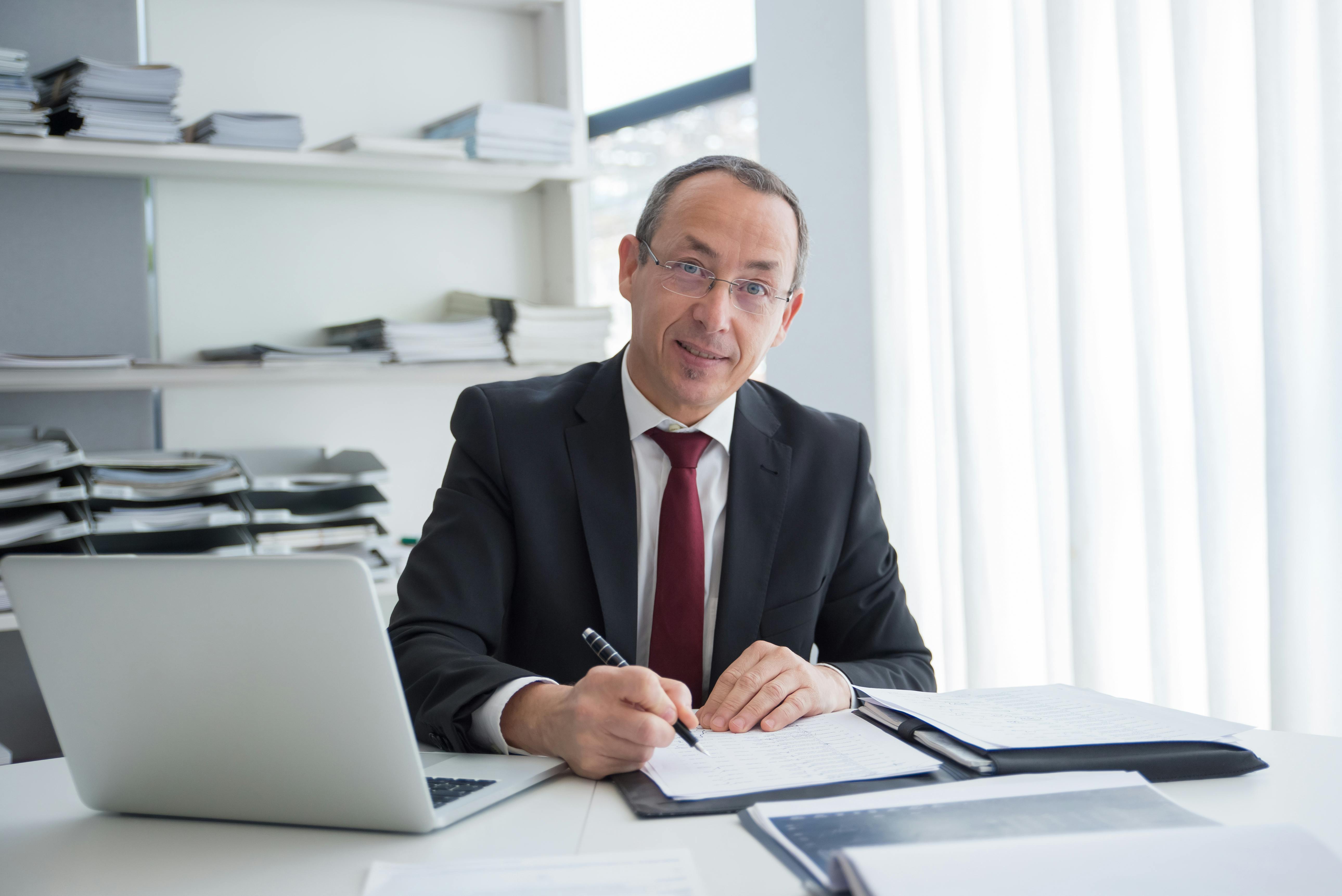 Un avocat souriant assis à une table | Source : Pexels