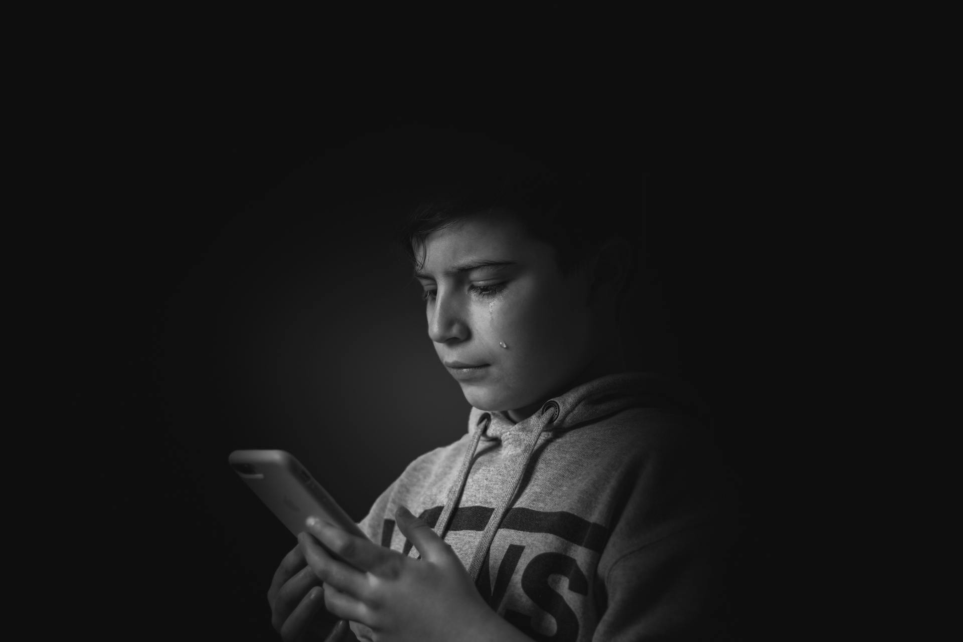 Un jeune garçon les larmes aux yeux regardant son téléphone | Source : Pexels