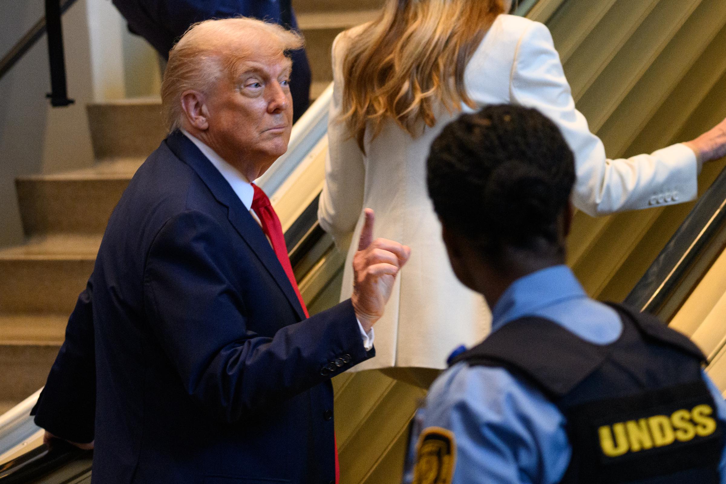 Donald Trump levant son index alors qu'il se trouve en bas de l'escalator. | Source : Getty Images