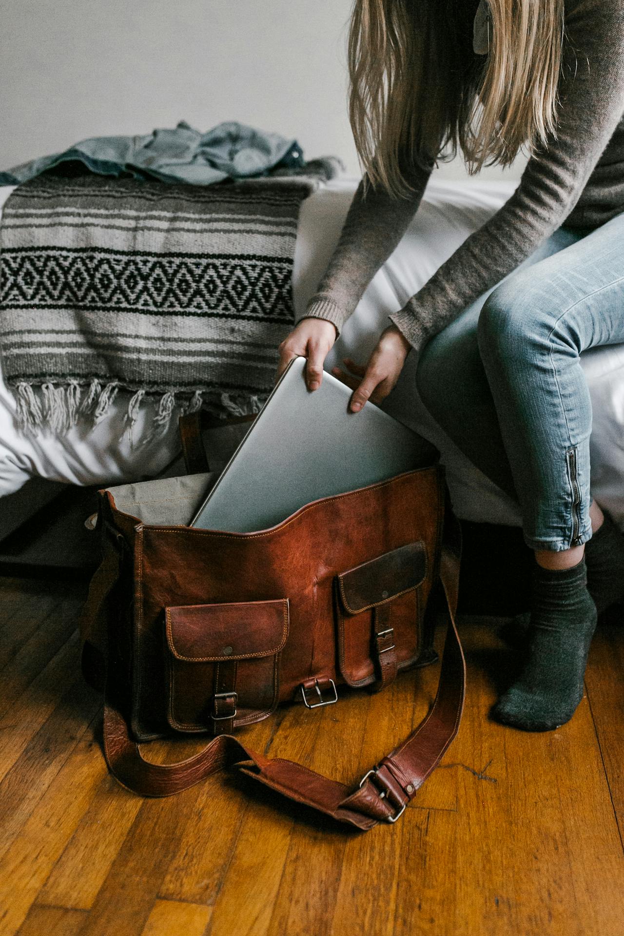 Une femme qui met un ordinateur portable dans un sac brun | Source : Pexels