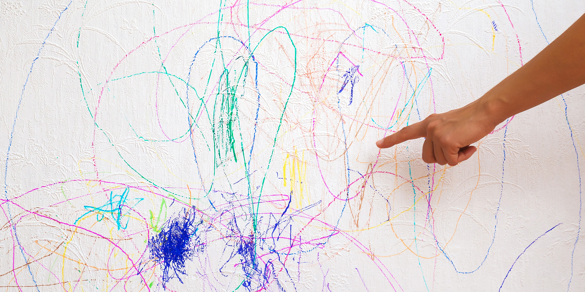 Un doigt montrant des rayures colorées sur un mur | Source : Shutterstock