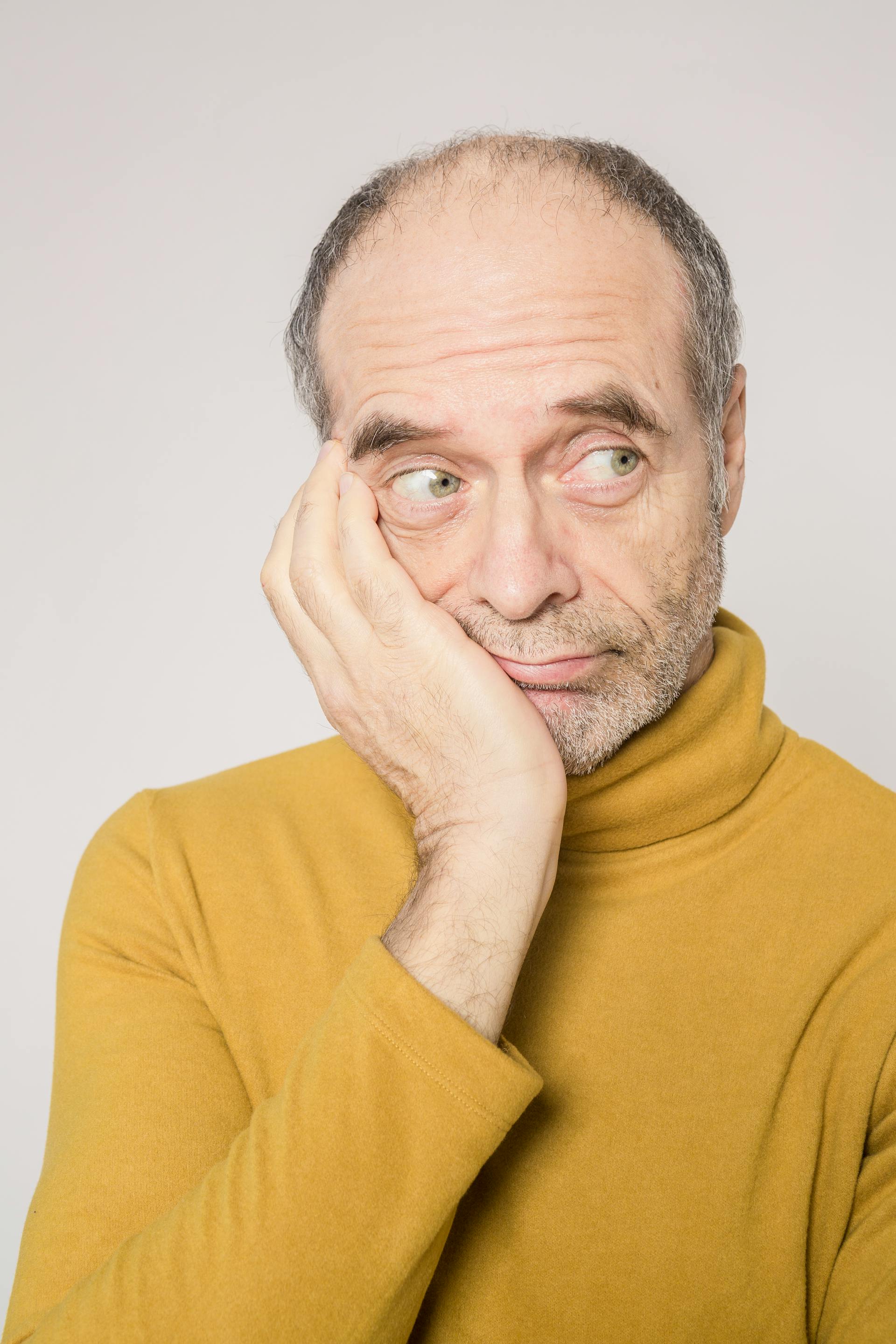 Un homme âgé avec un pull jaune qui regarde de côté | Source : Pexels