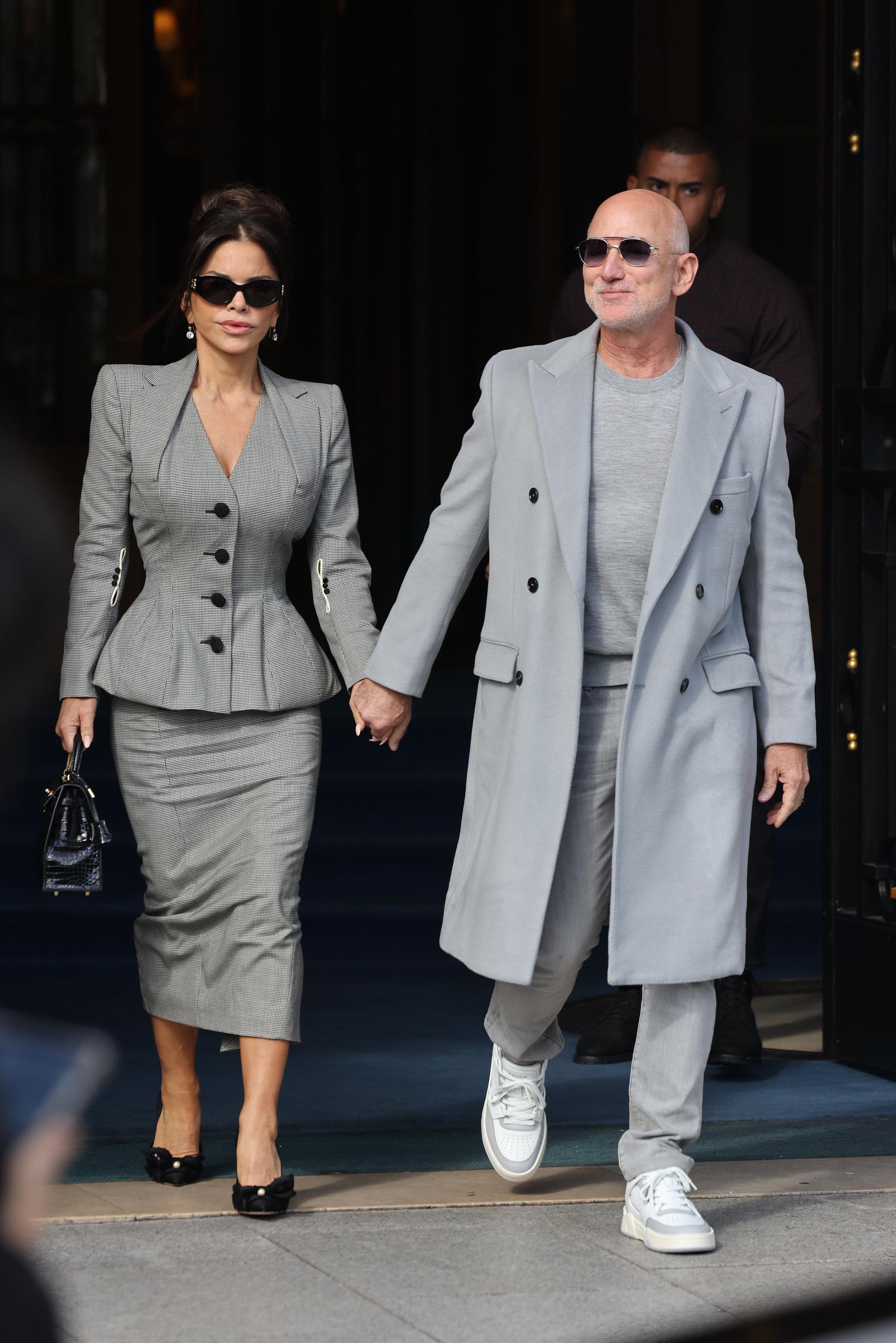 Lauren Sánchez et Jeff Bezos ont été aperçus quittant l'hôtel Ritz lors des défilés printemps-été 2026 pour femmes de la Fashion Week de Paris, en France. Jeff Bezos arborait un look décontracté, composé d'un t-shirt et d'un jean sous un manteau à poches, assorti de lunettes de soleil et de baskets. Lauren portait un tailleur à carreaux avec un blazer à basques et une jupe crayon. Tous deux complétaient leur tenue avec des lunettes de soleil foncées.