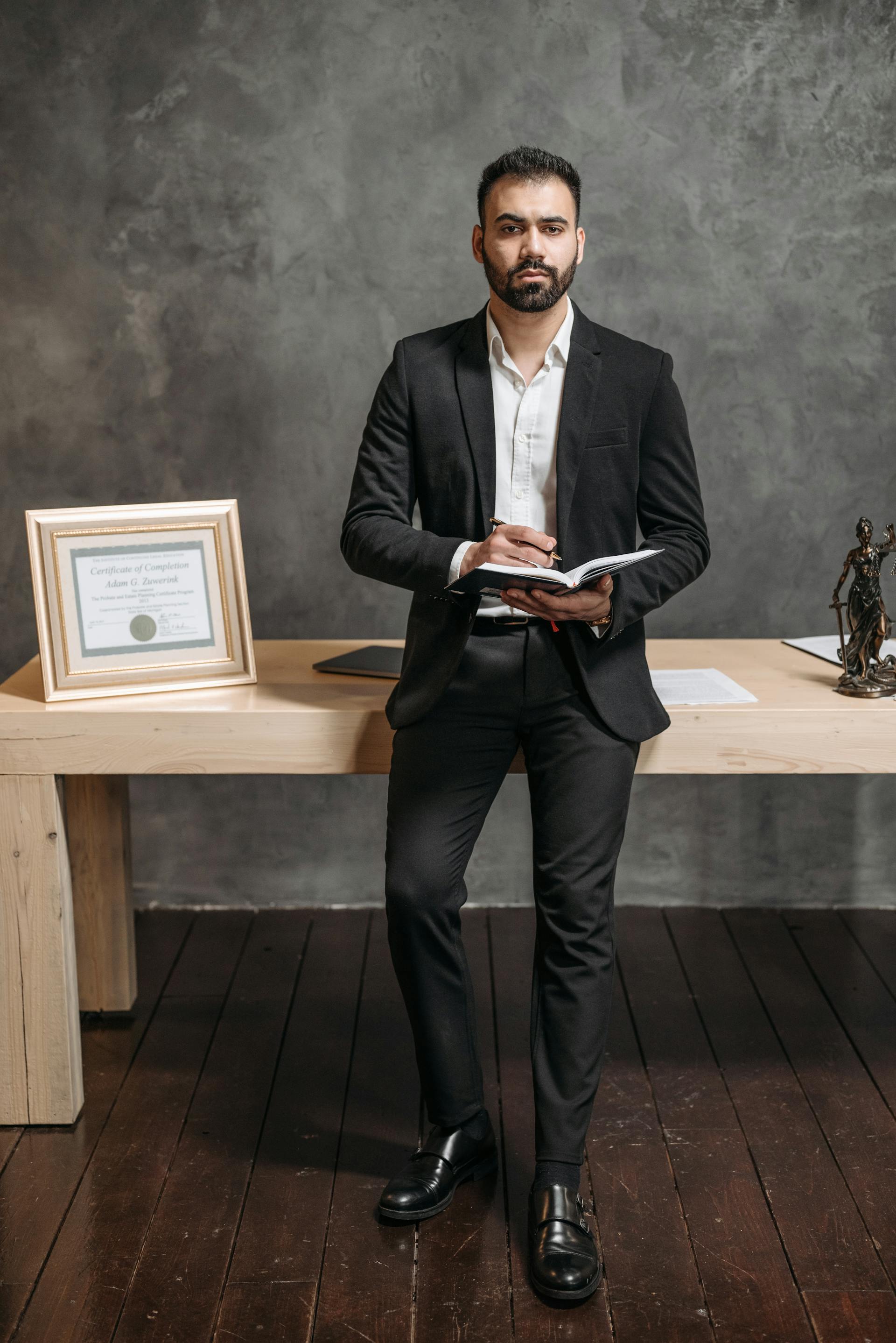 Homme en costume noir tenant un carnet de notes | Source : Pexels