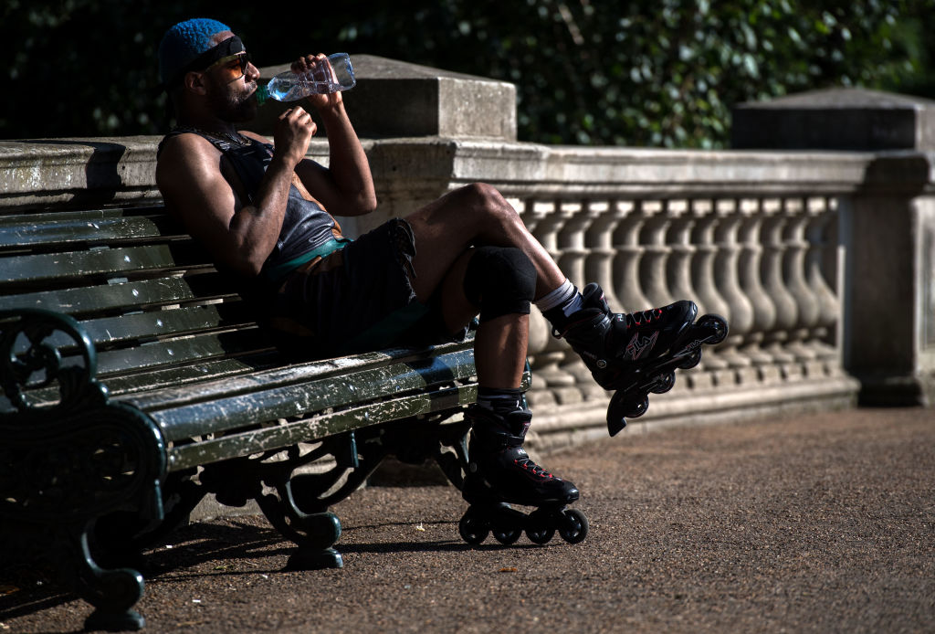 Un homme sur un banc en train de boire de l'eau | Source : Getty Images