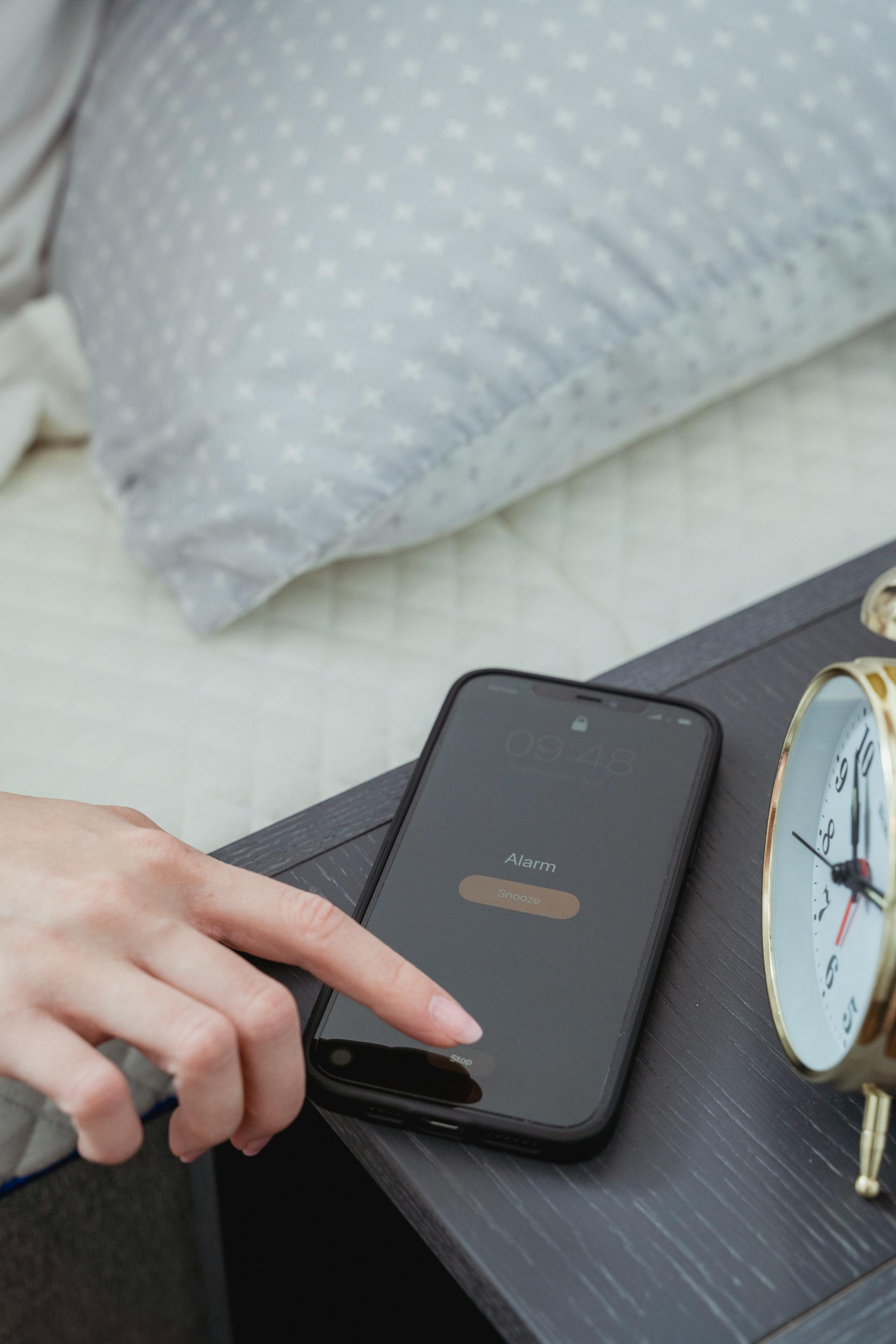 Gros plan d'une femme qui désactive l'alarme de son smartphone | Source :