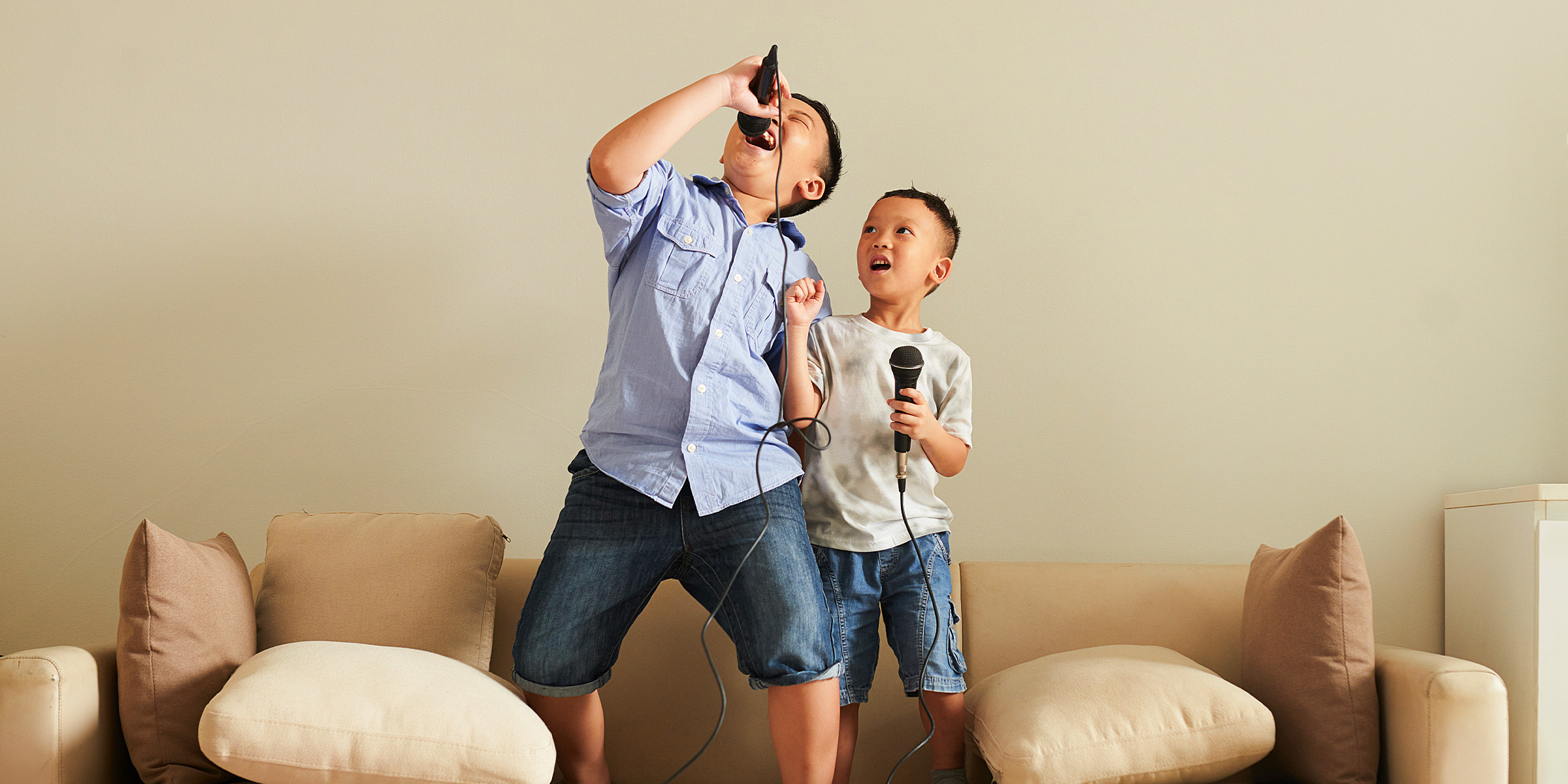 Deux jeunes garçons tenant des microphones et se détendant ensemble | Source : Shutterstock