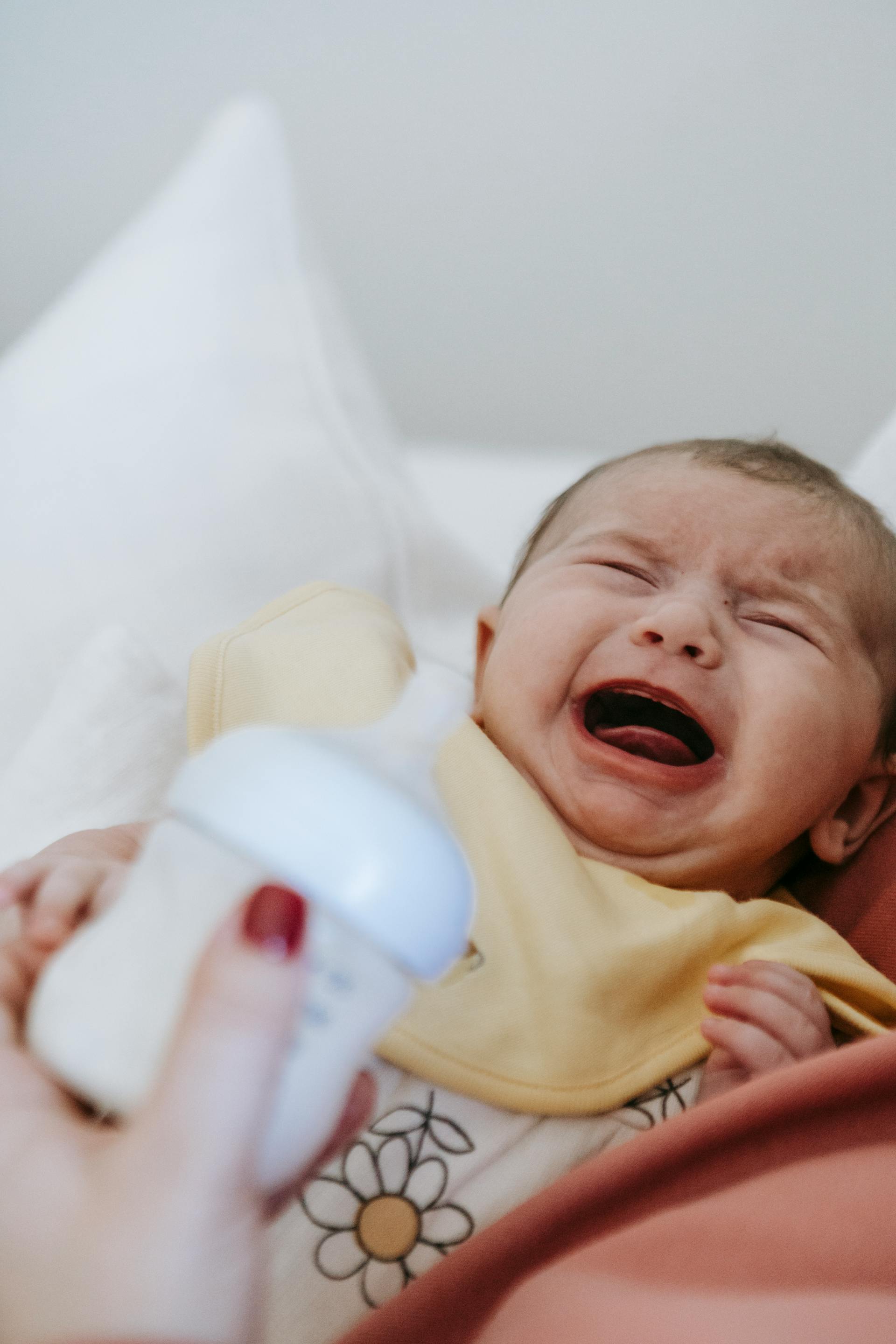 Une femme tenant un bébé qui pleure et un biberon | Source : Pexels