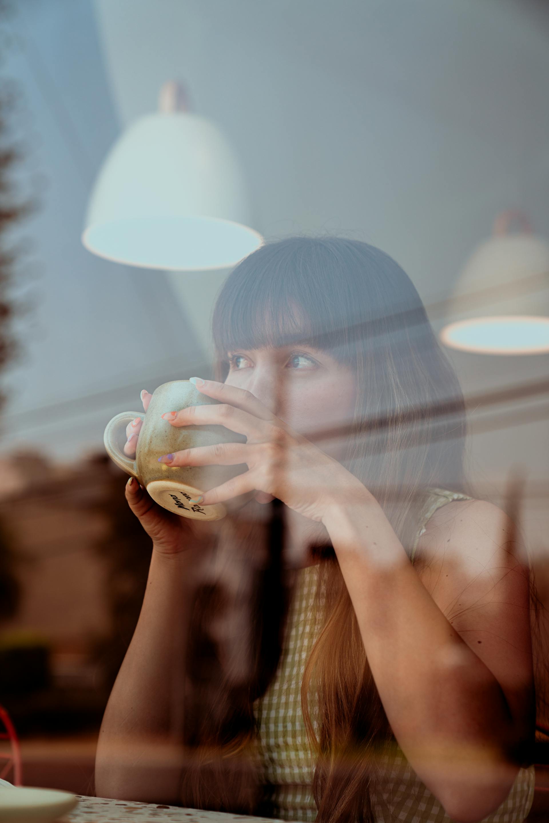Une femme buvant un café et regardant par la fenêtre du café | Source : Pexels