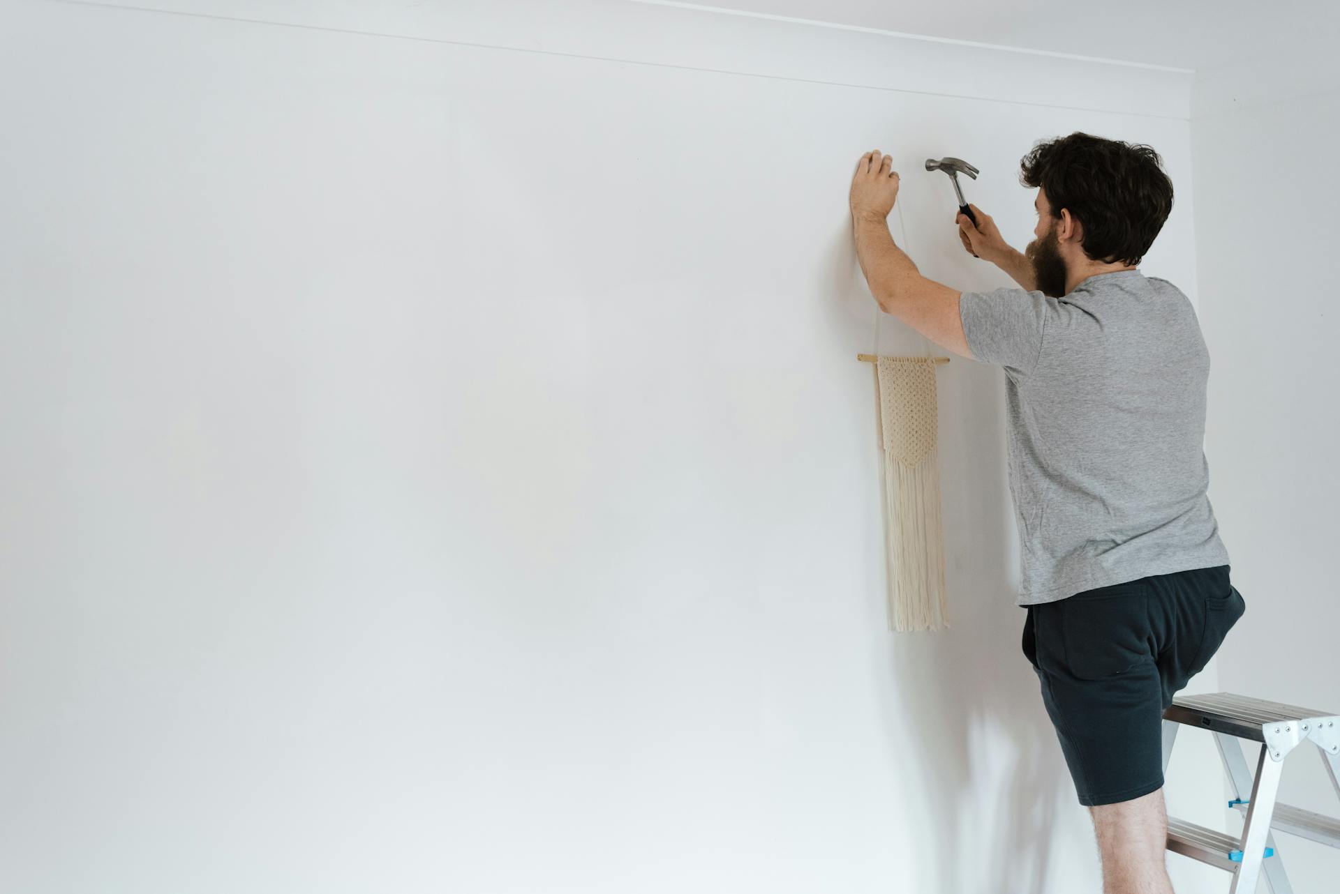 Un homme qui pose un élément de décor sur un mur | Source : Pexels