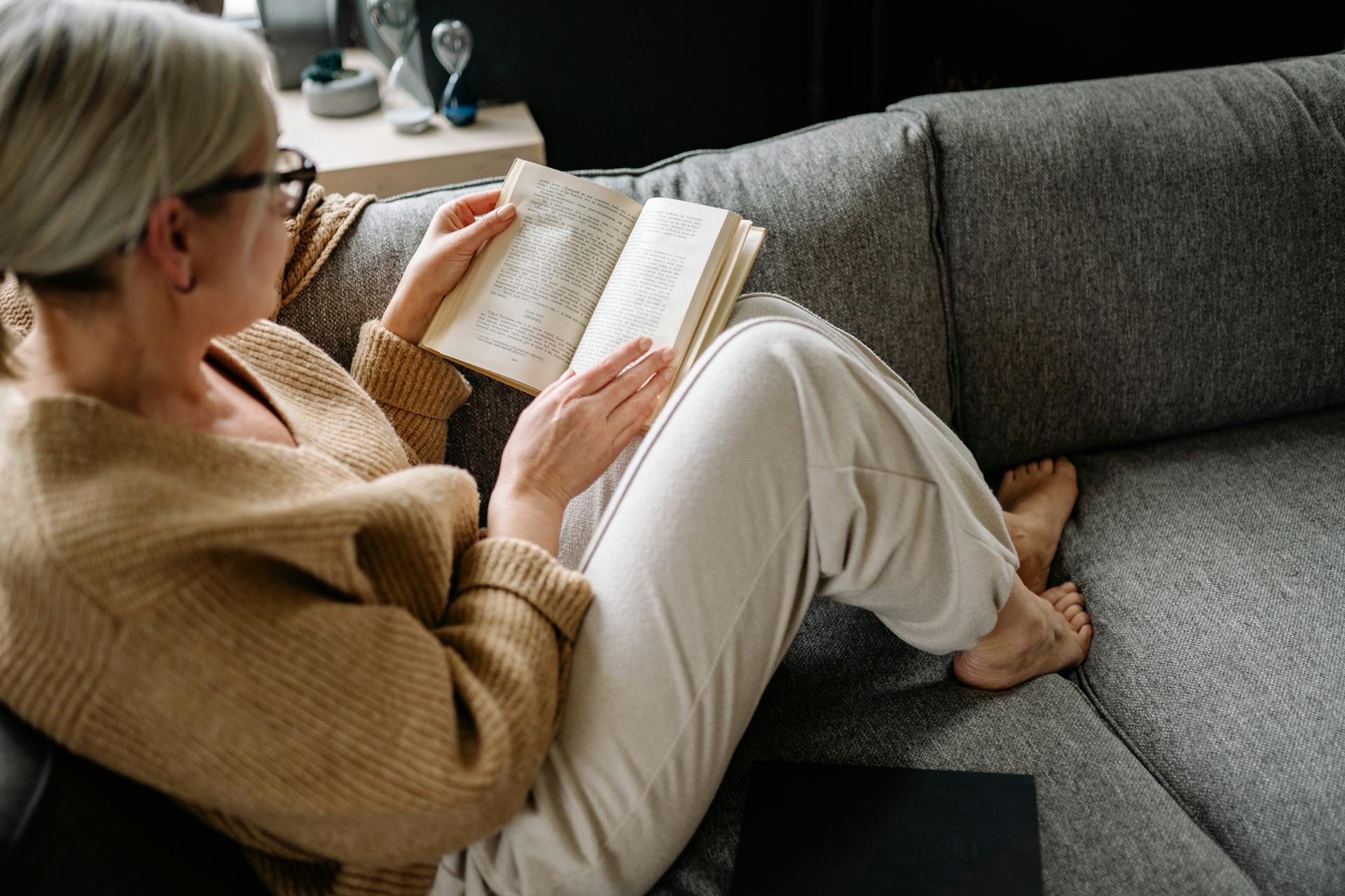 Une femme âgée lisant un livre assise sur un canapé | Source : Pexels