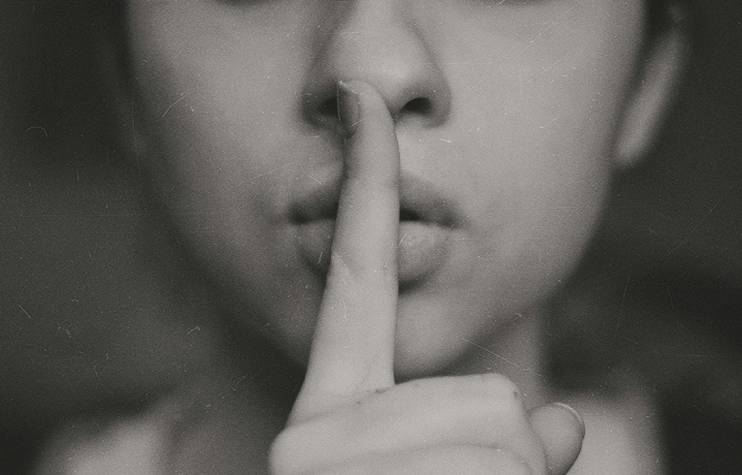 Photo en niveaux de gris d'une femme faisant un signe silencieux de la main | Source : Unsplash