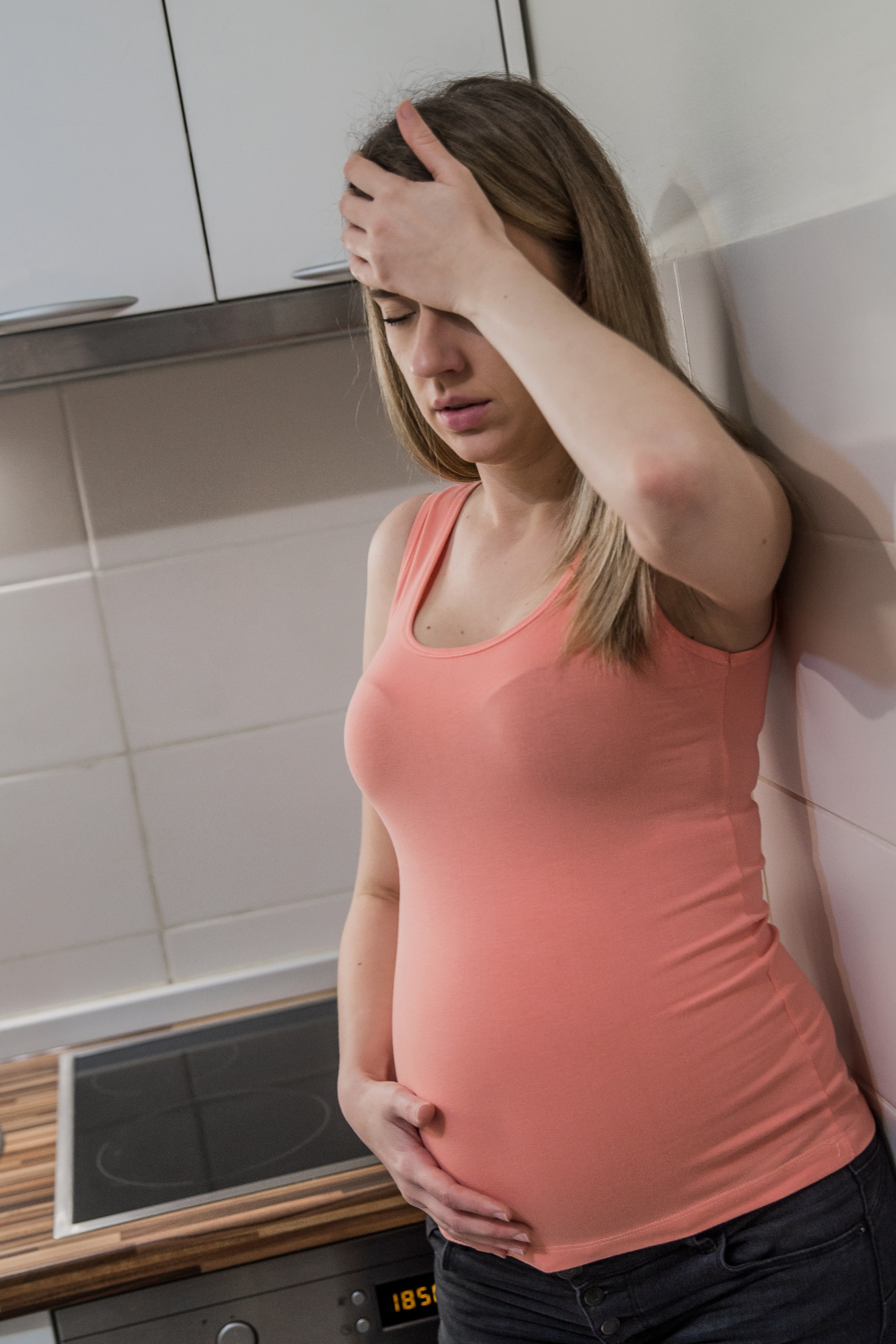 Une femme enceinte stressée debout dans la cuisine | Source : Freepik
