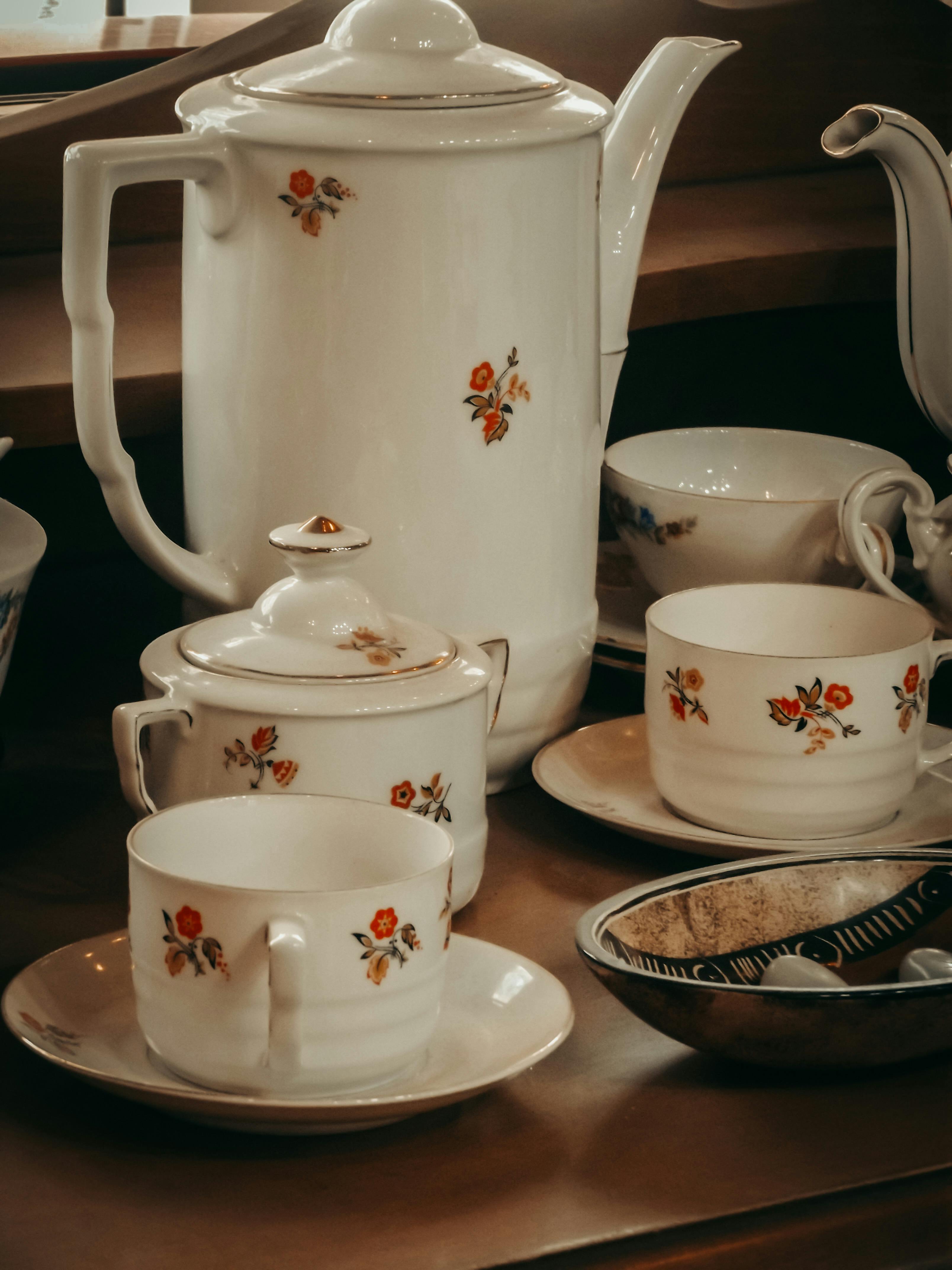 Un service à thé blanc avec des fleurs rouges | Source : Pexels