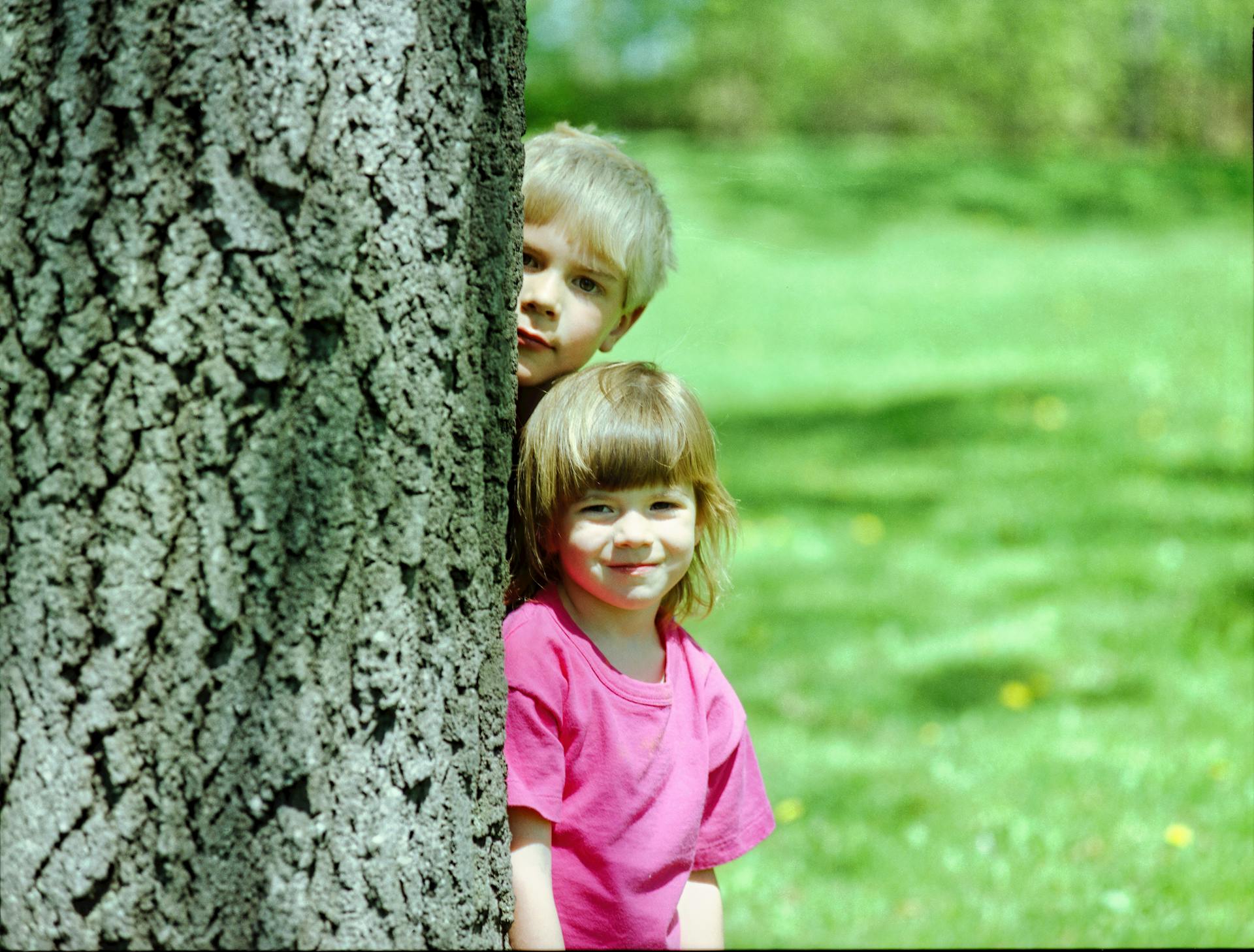 Un garçon et une fille debout derrière un arbre | Source : Pexels