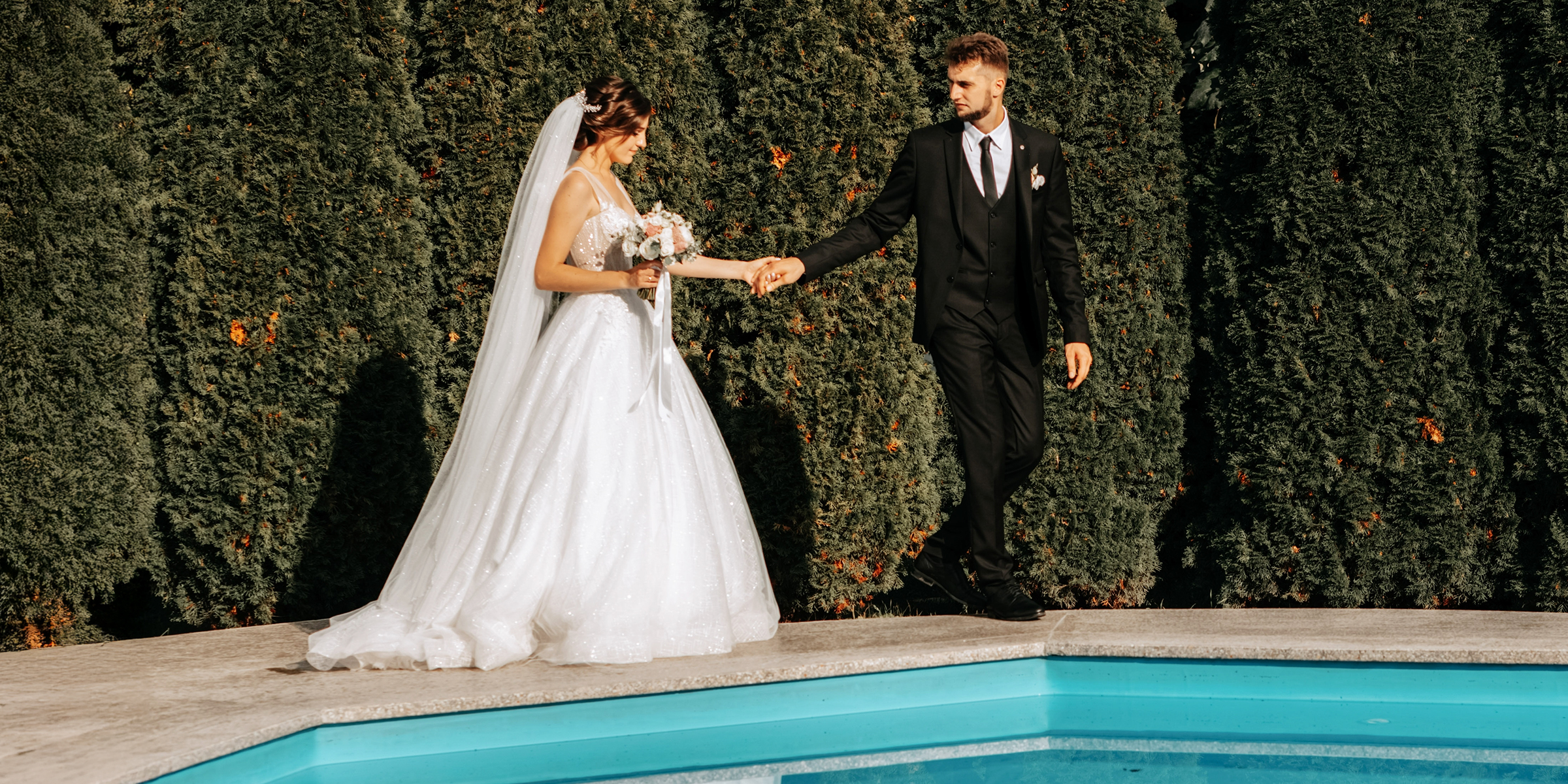 Un couple de jeunes mariés au bord d'une piscine | Source : Shutterstock