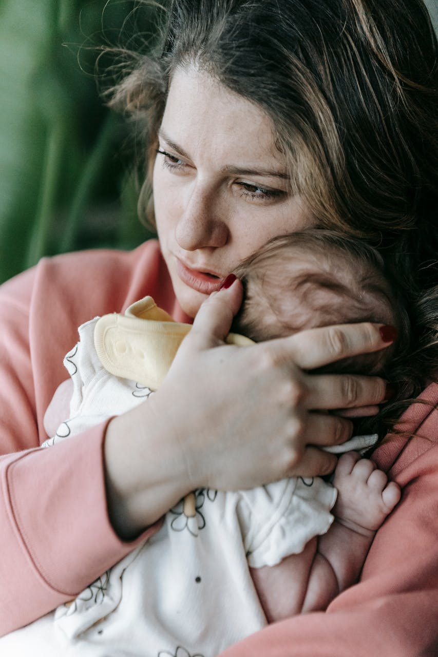 Une mère perdue dans ses pensées profondes alors qu'elle tient son bébé | Source : Pexels