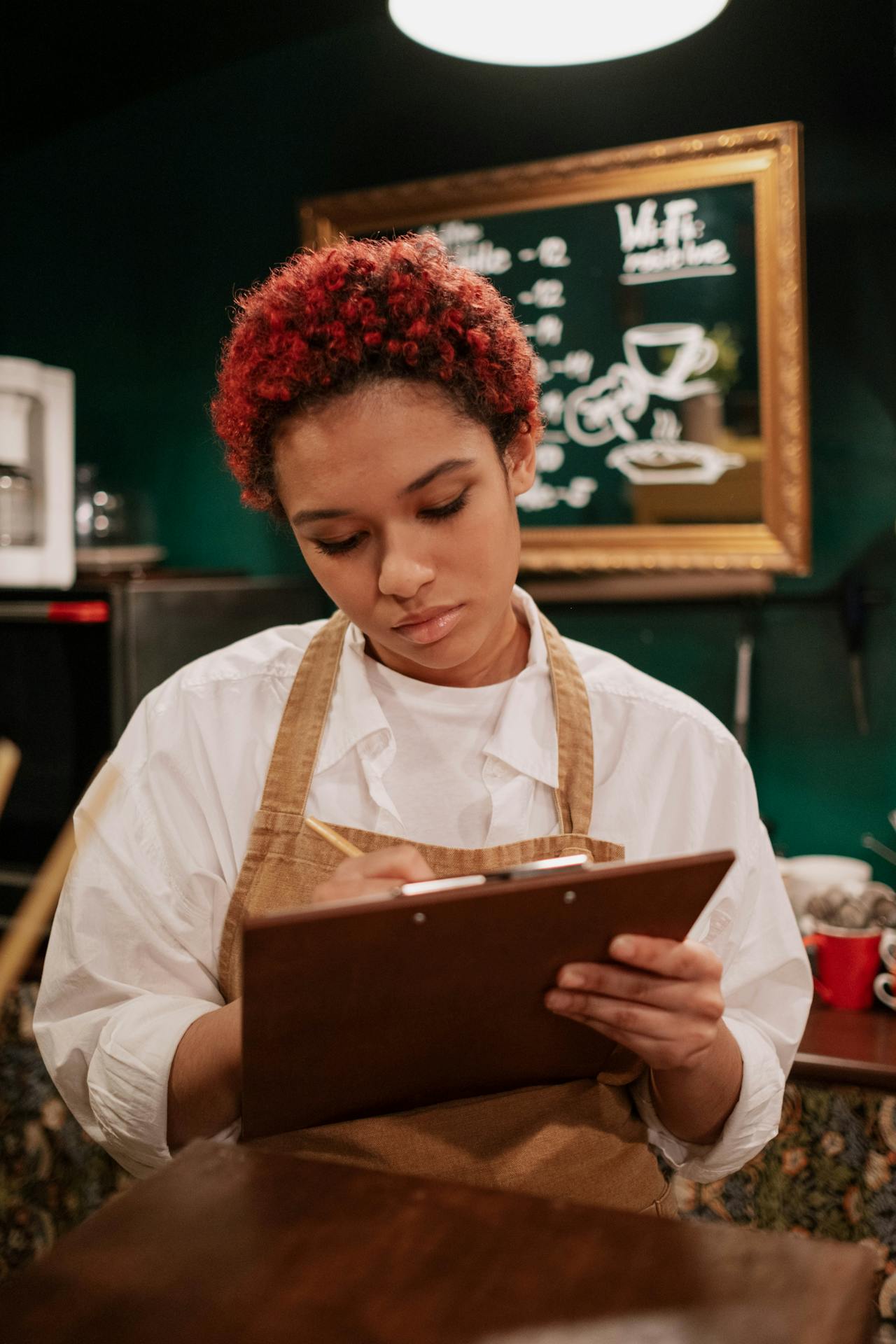 Une femme en tablier prenant une commande dans un restaurant | Source : Pexels