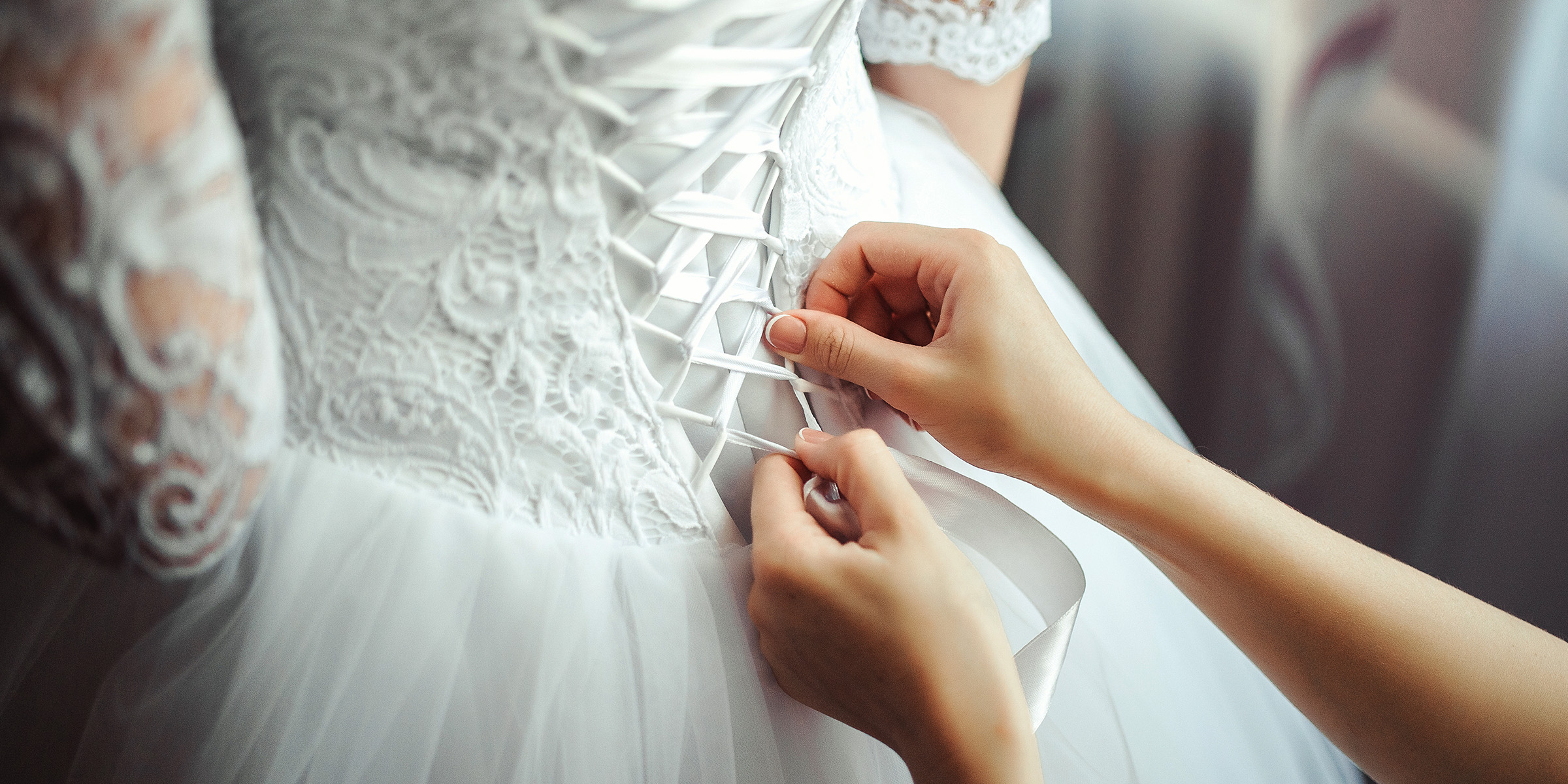 Une femme laçant le corsage d'une robe de mariée | Source : Freepik