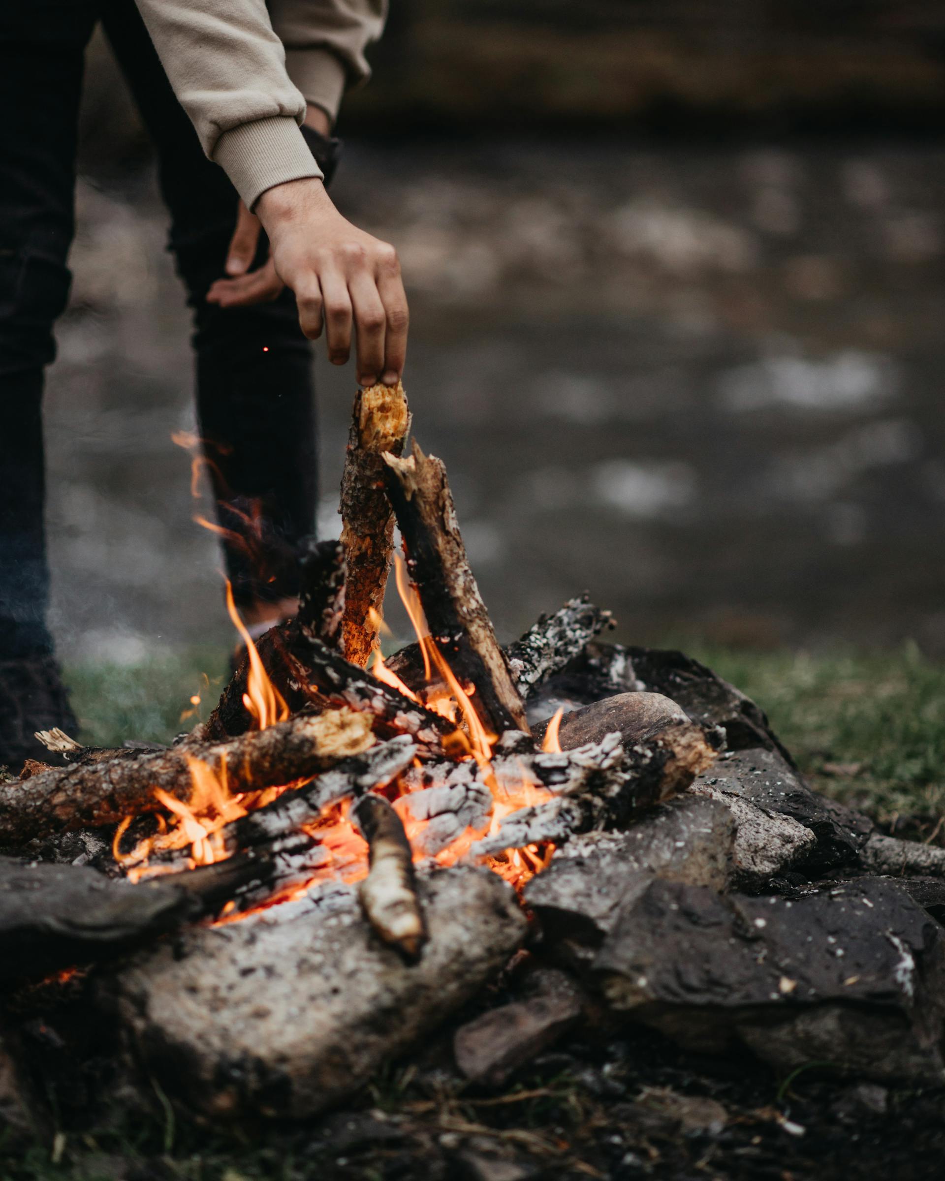 Un homme ajoutant du bois à un feu | Source : Pexels