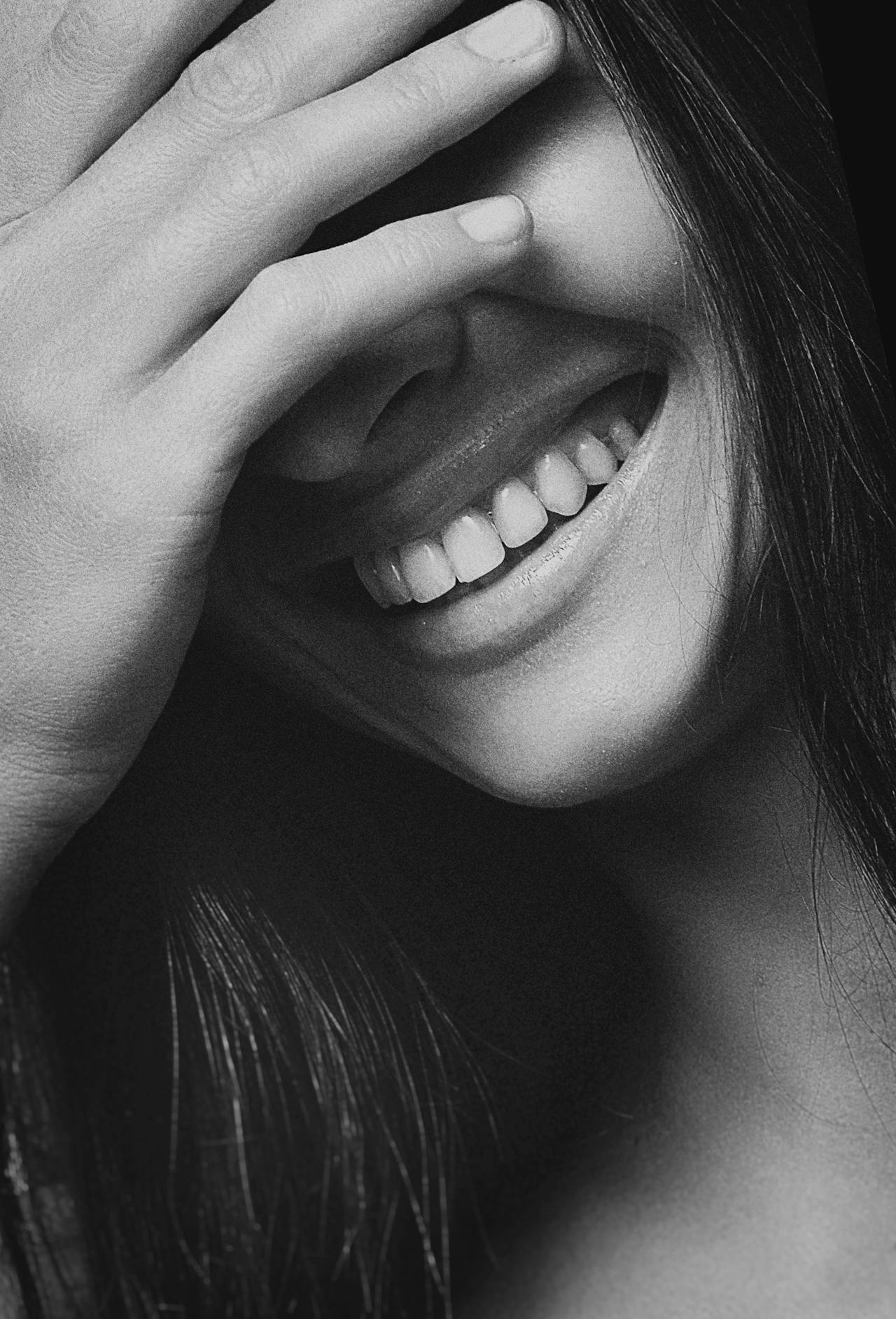 Photo en niveaux de gris d'une jeune femme qui rit | Source : Pexels