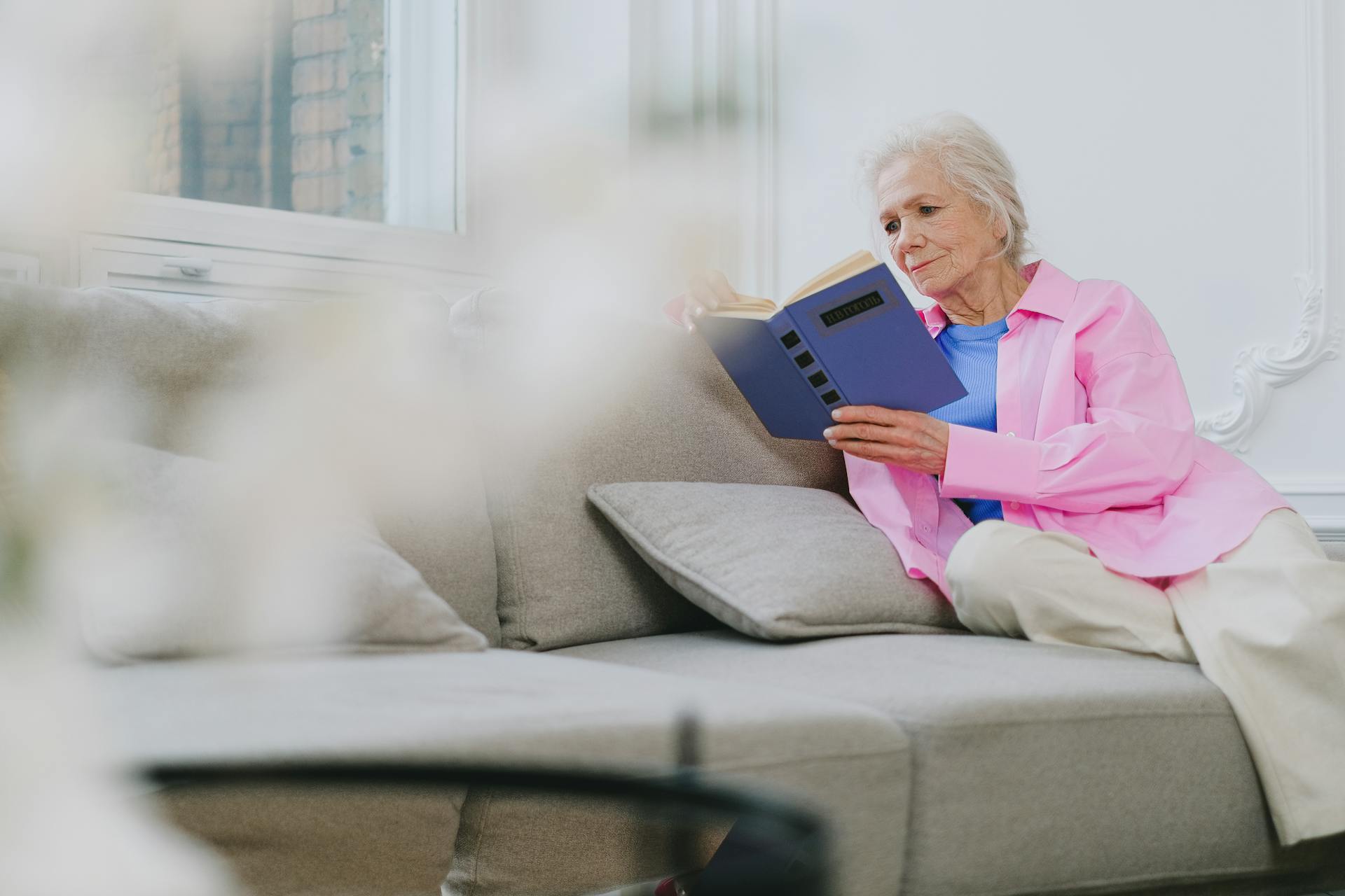 Une femme âgée assise sur le canapé et lisant un livre | Source : Pexels
