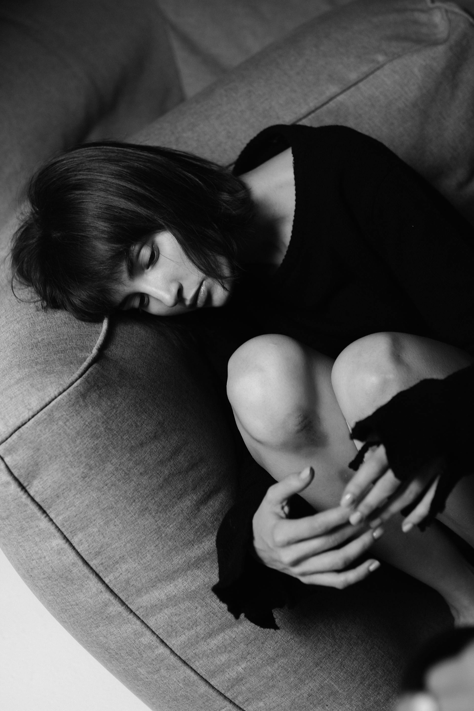 Photo en niveaux de gris d'une femme allongée sur le canapé | Source : Pexels