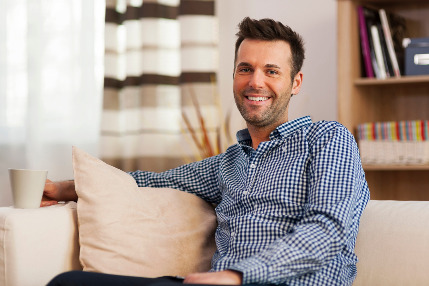 Un homme assis sur le canapé et souriant | Source : Freepik