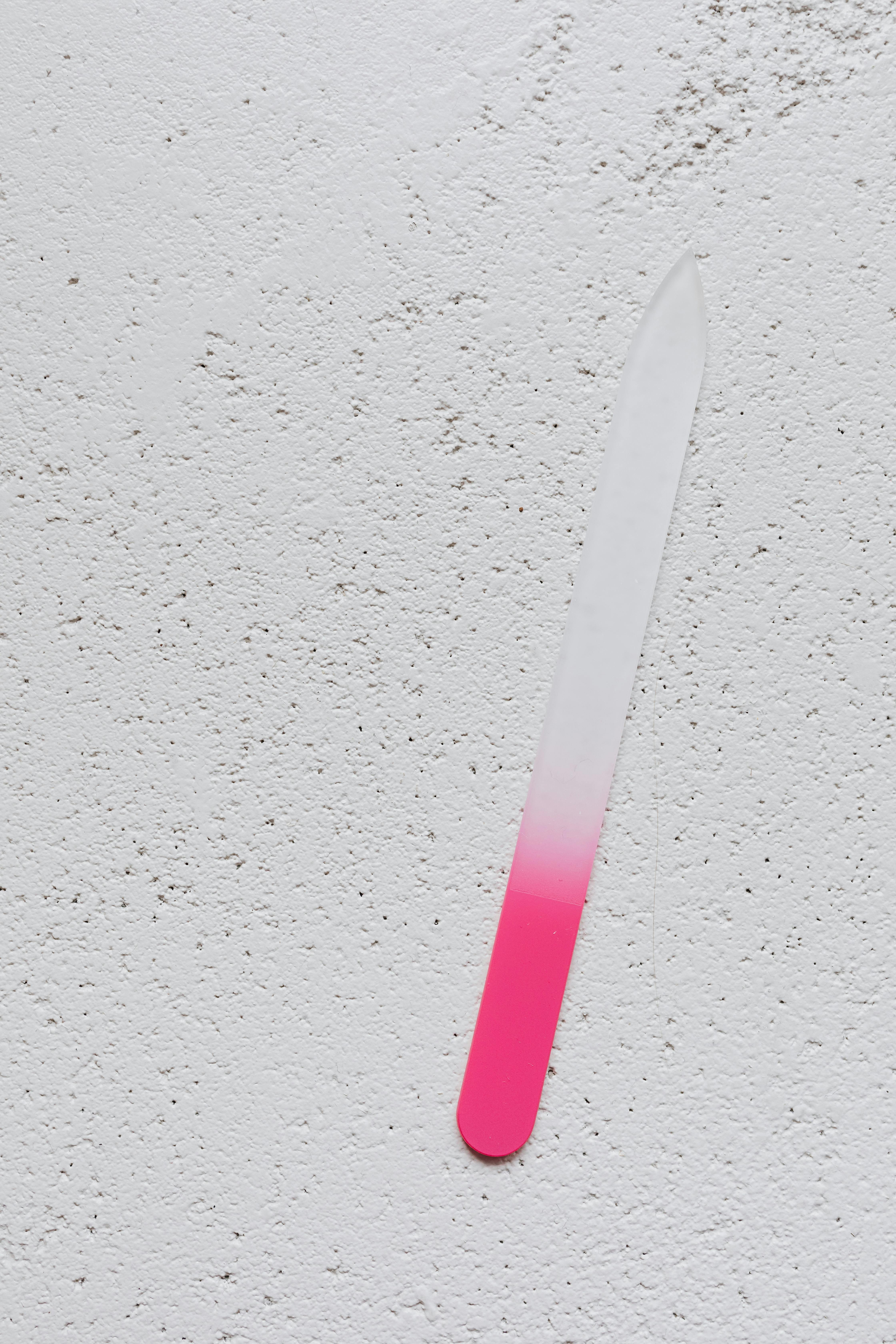 Une lime à ongles rose et blanche sur une table | Source : Pexels
