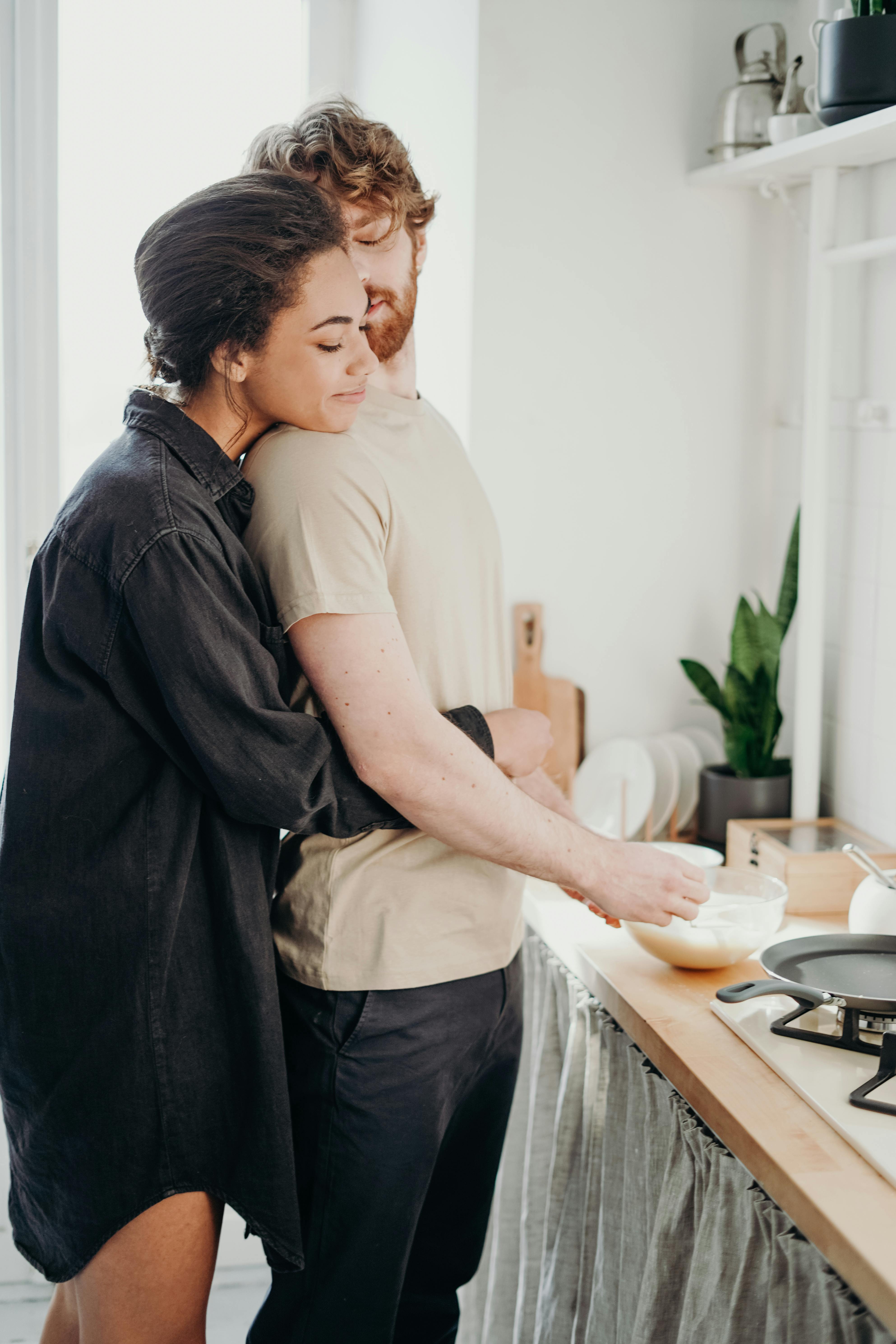 Une femme qui serre son homme dans ses bras pendant qu'il prépare le petit déjeuner | Source : Pexels