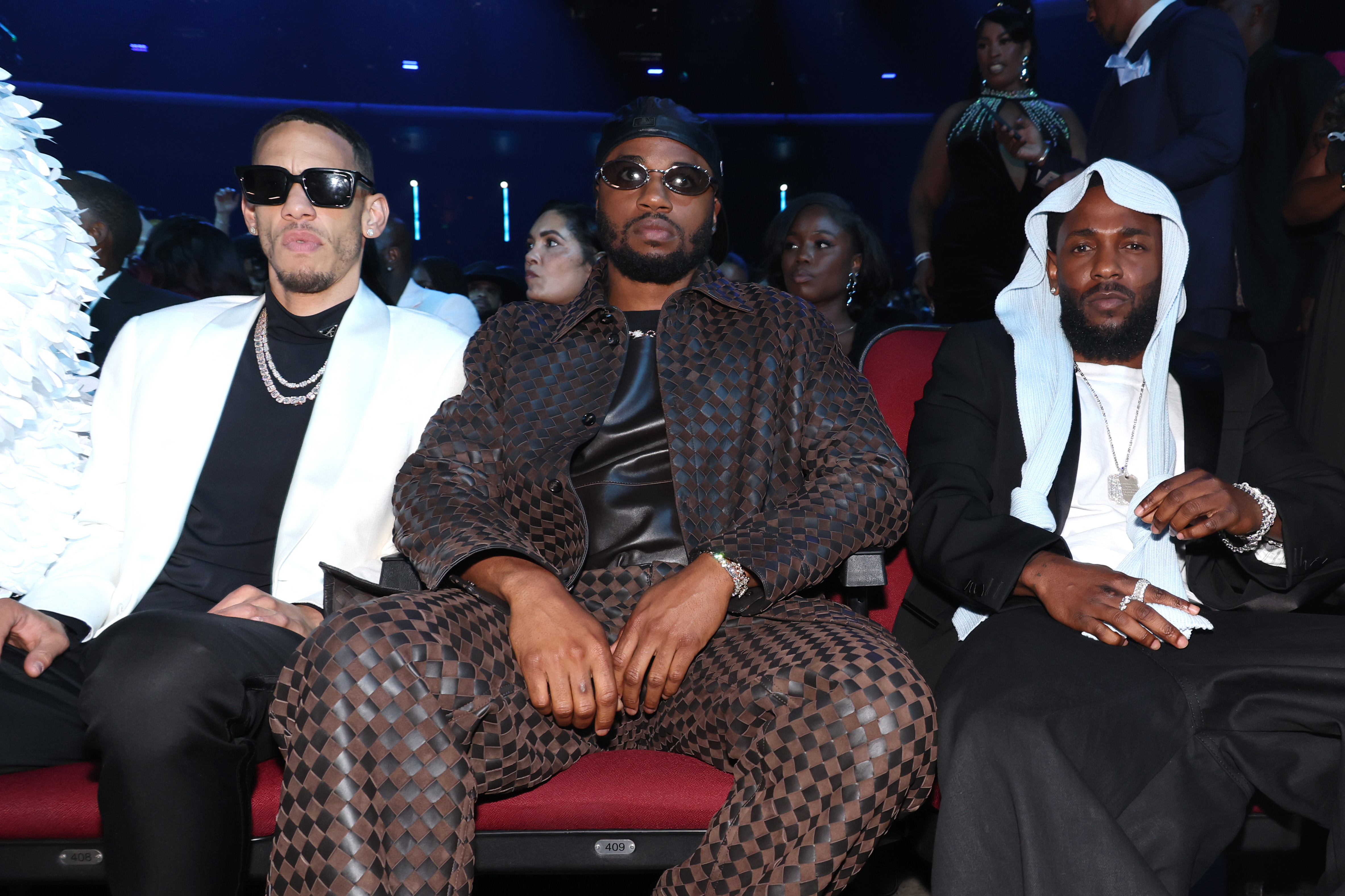 Assis au premier rang des BET Awards 2025, Kendrick Lamar pose avec ses collègues King Matta et Dave Free, dans une ambiance détendue et sereine. Il arborait son couvre-chef désormais viral, assorti d'un élégant costume noir et d'une chemise blanche.